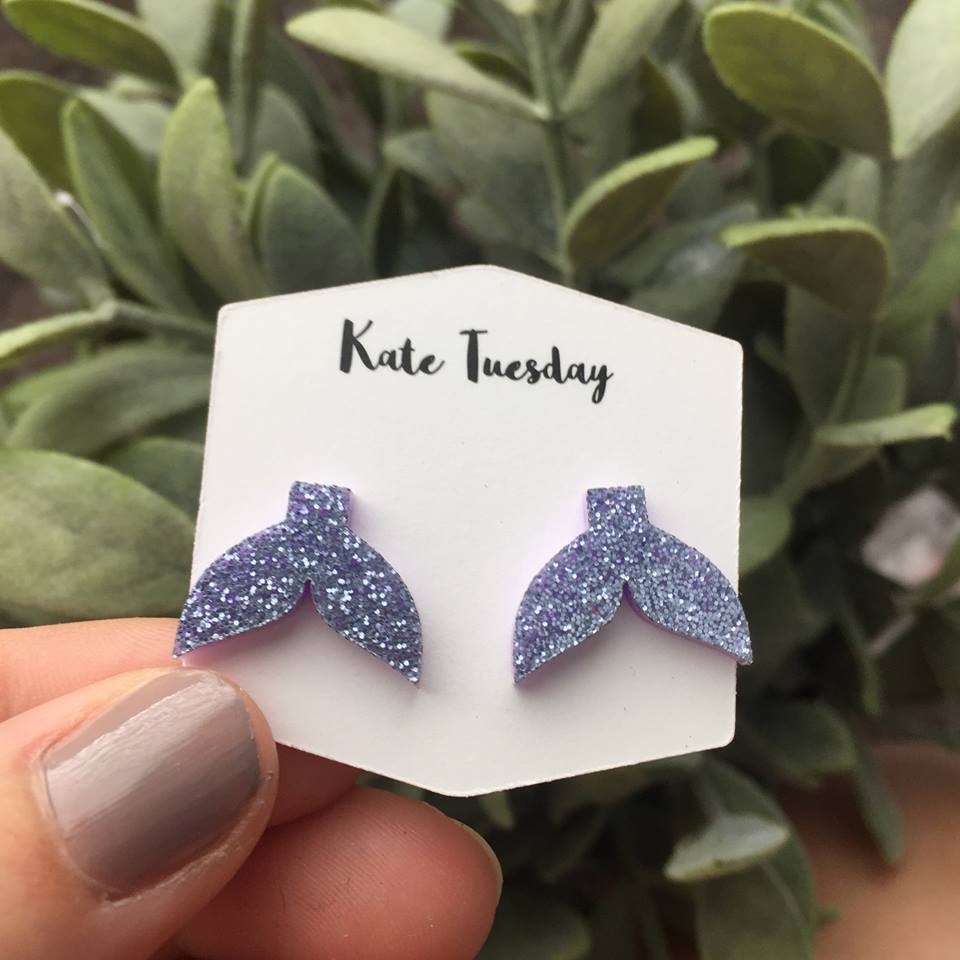 Purple sparkly acrylic stud earrings shaped like mermaid tails, showcasing a vibrant design with a shimmering finish.