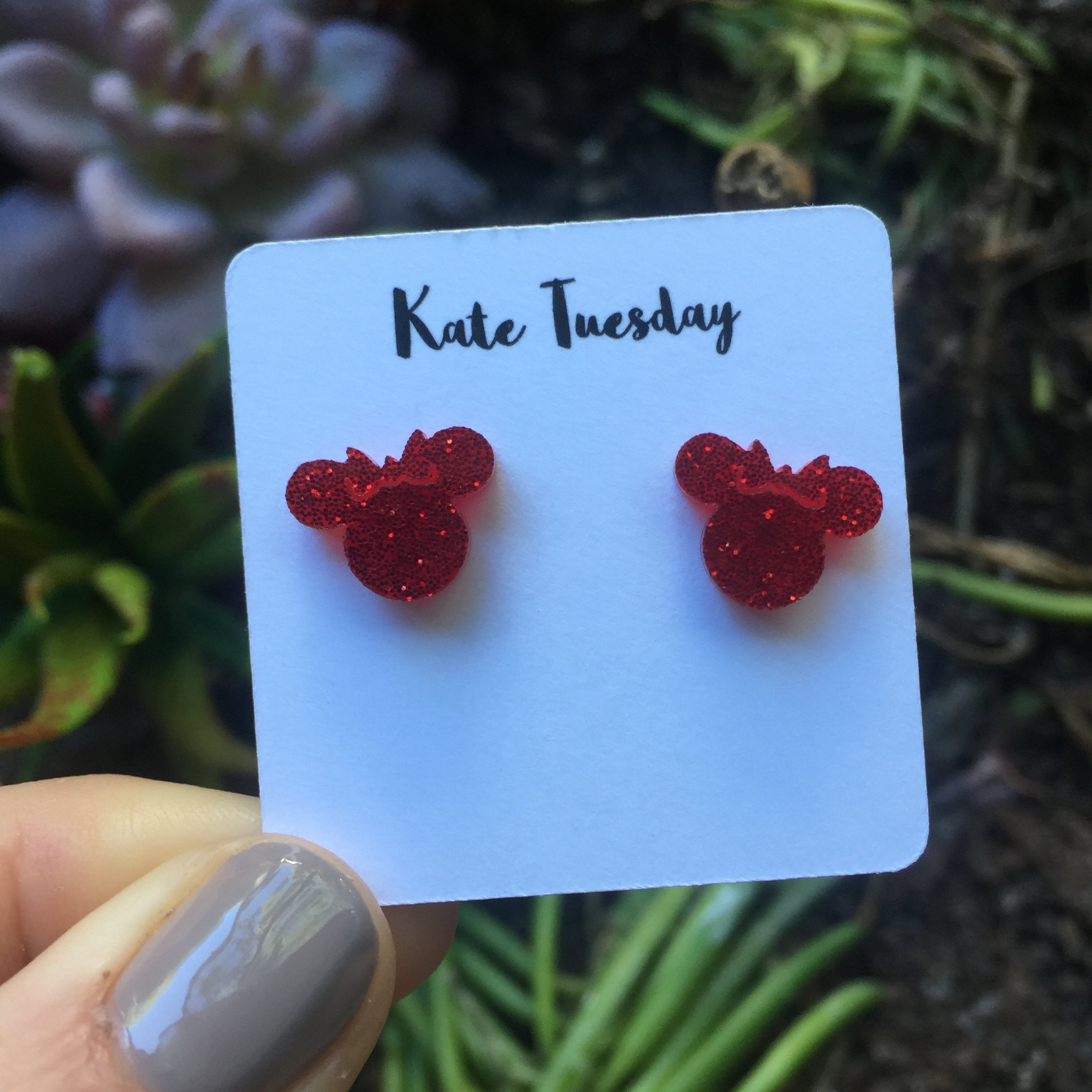 A pair of vibrant red acrylic stud earrings shaped like a playful mouse, featuring sparkly details.