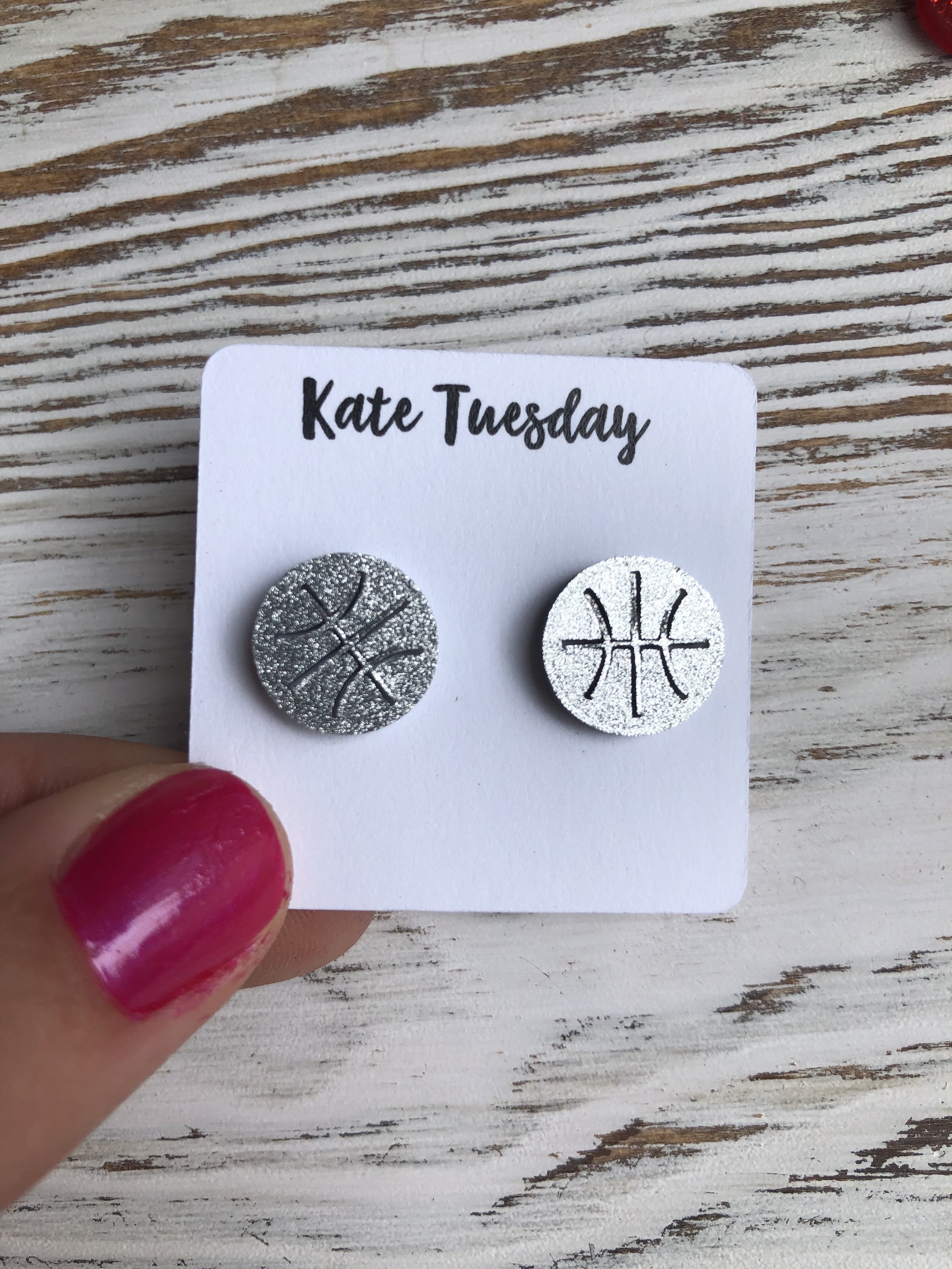 A pair of sparkly silver basketball-themed stud earrings made from acrylic, showcasing a vibrant and eye-catching design.