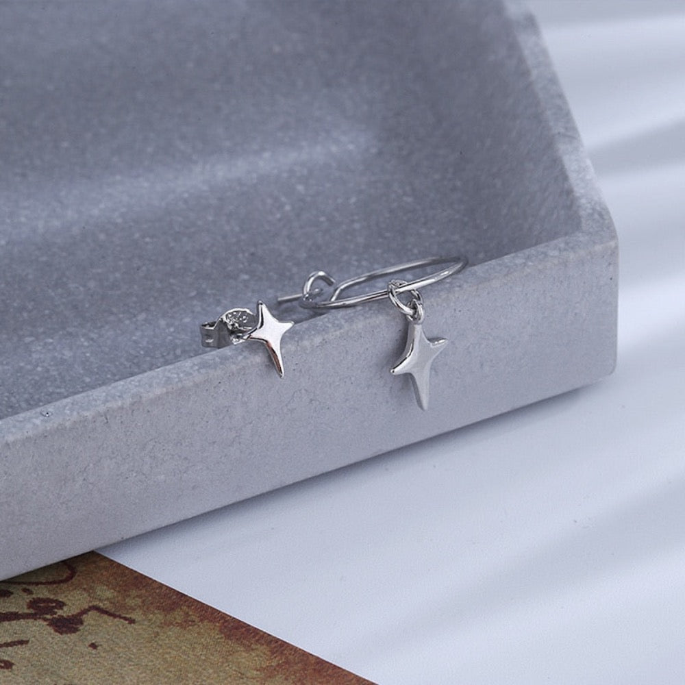 A pair of asymmetrical star earrings featuring one hoop star earring and one star stud, crafted from silver-colored copper and metal.