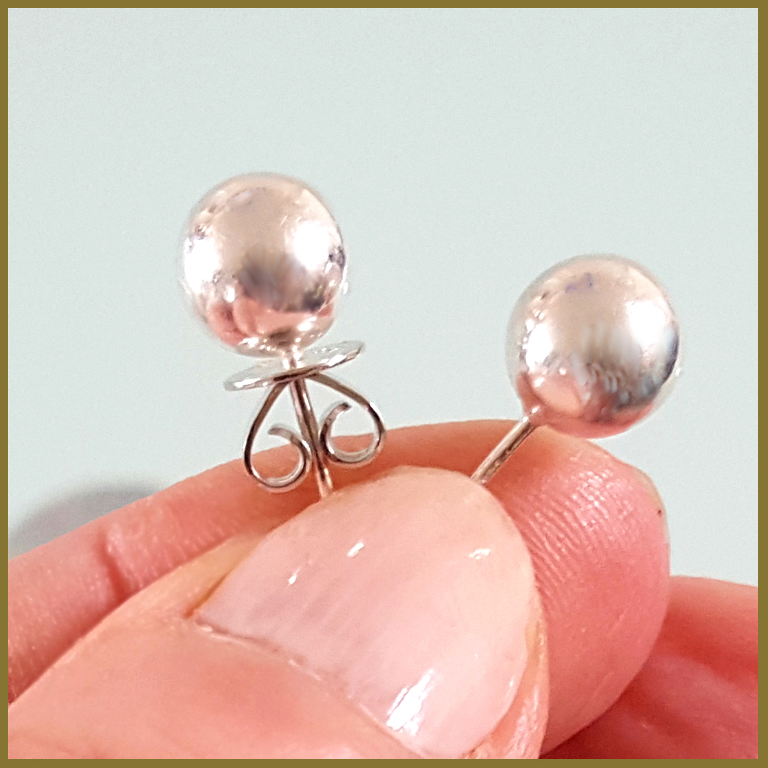 A pair of elegant sterling silver 8 mm ball stud earrings with a shiny finish, displayed on a soft fabric background.