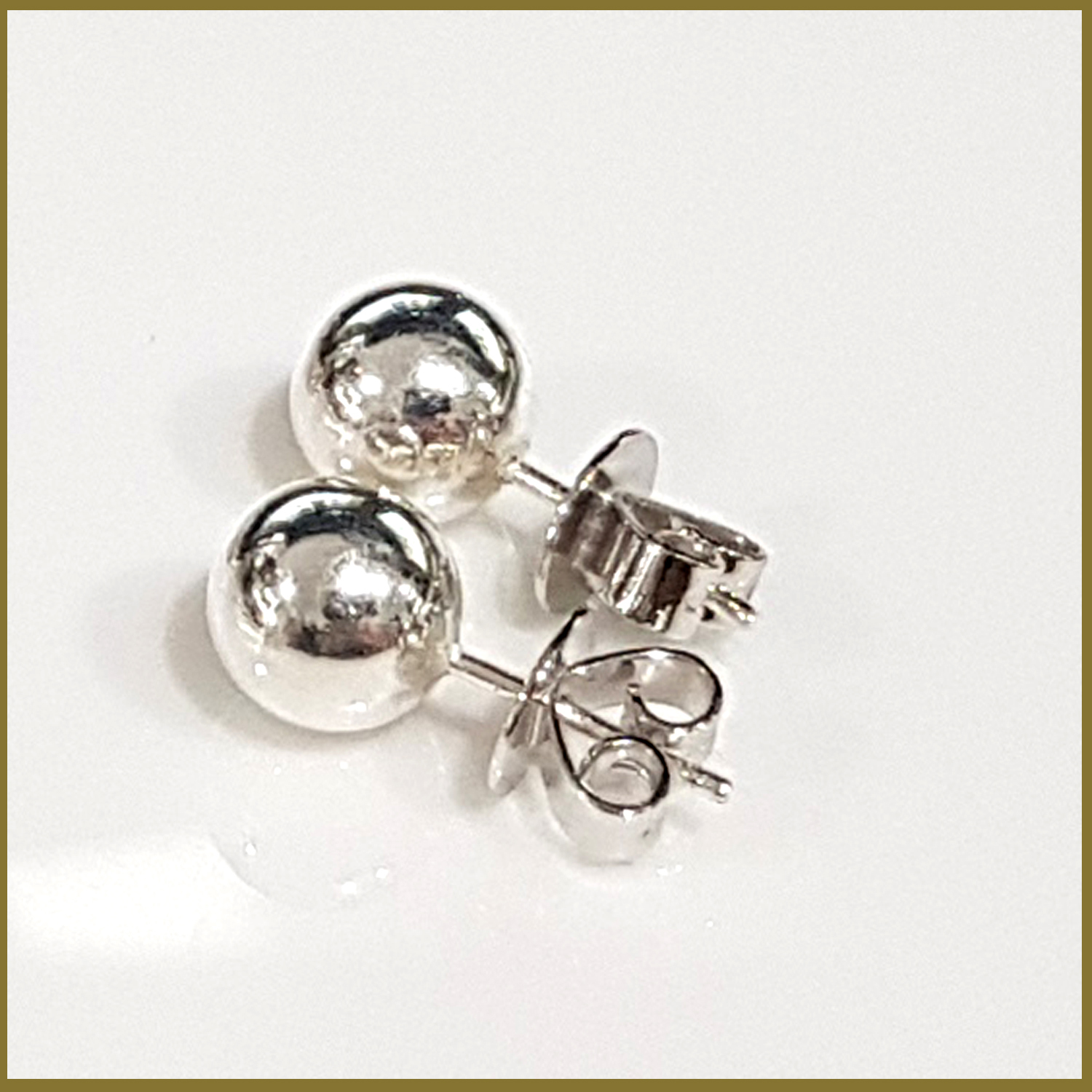 A pair of elegant sterling silver 8 mm ball stud earrings with a shiny finish, displayed on a soft fabric background.