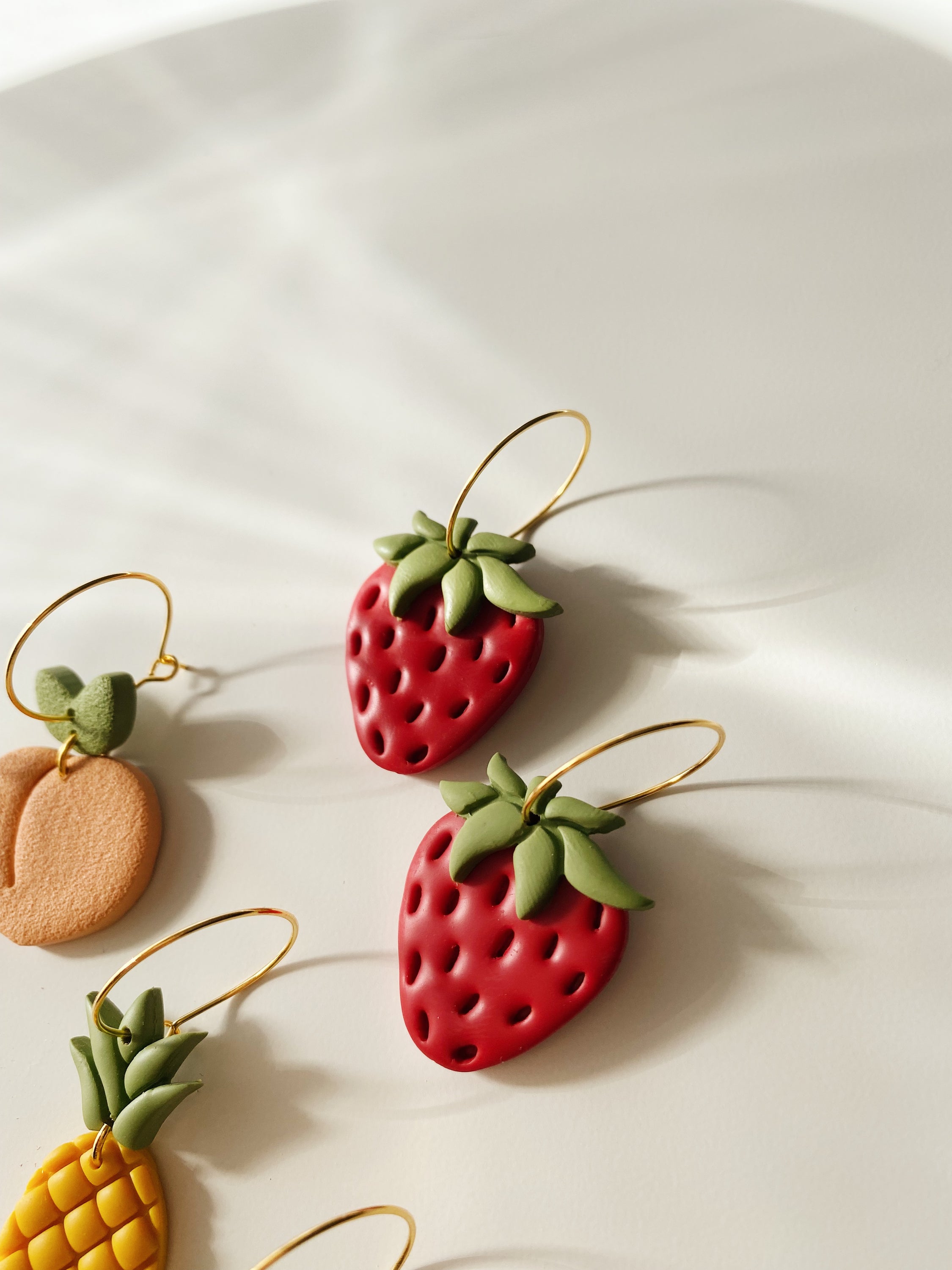 A pair of handcrafted Strawberry Hoops earrings, featuring lightweight and hypoallergenic posts, showcasing unique variations and imperfections.