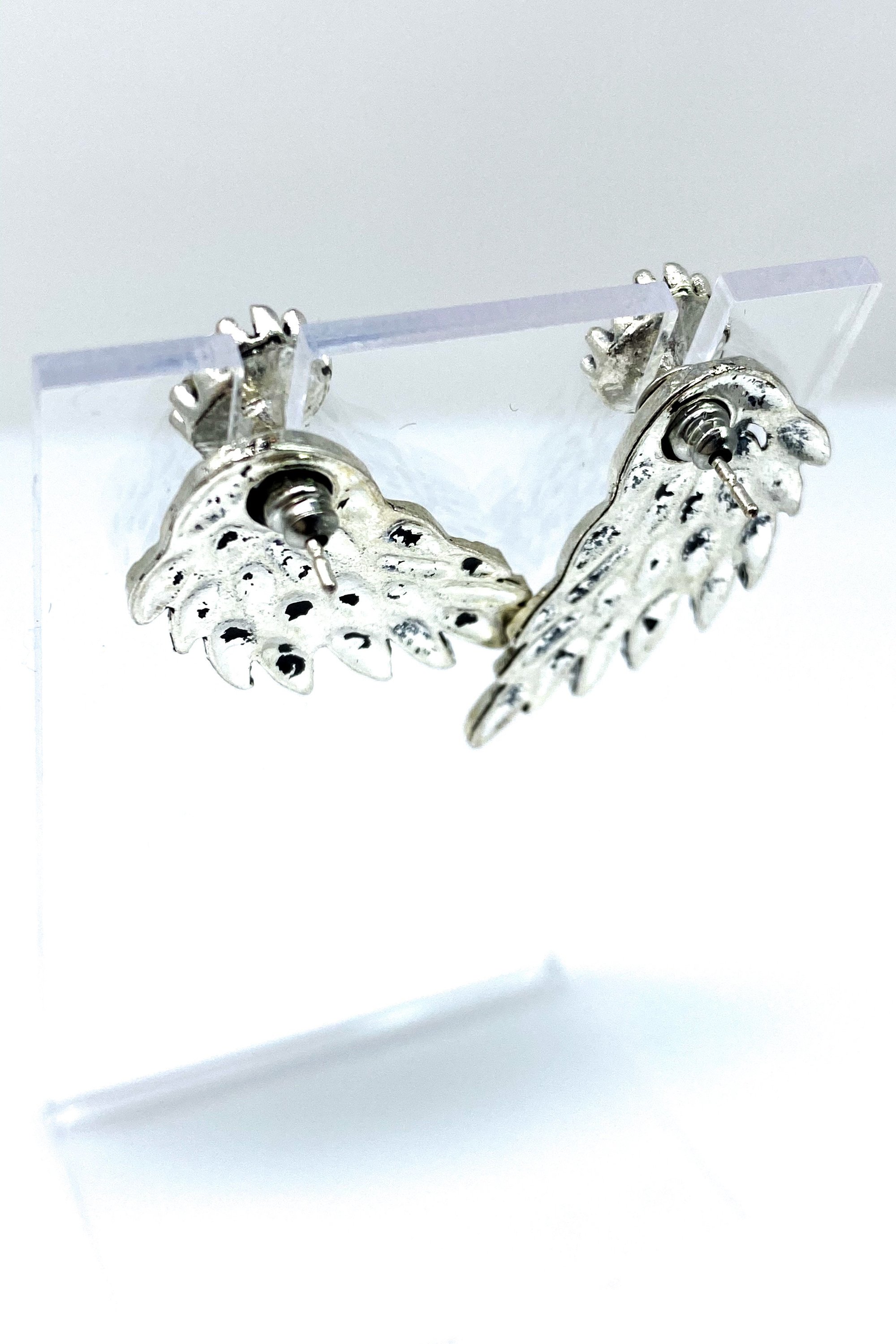 A pair of 420 Wingz Earrings featuring a unique wing design with a diamond accent, available in gold, silver, and black colors.