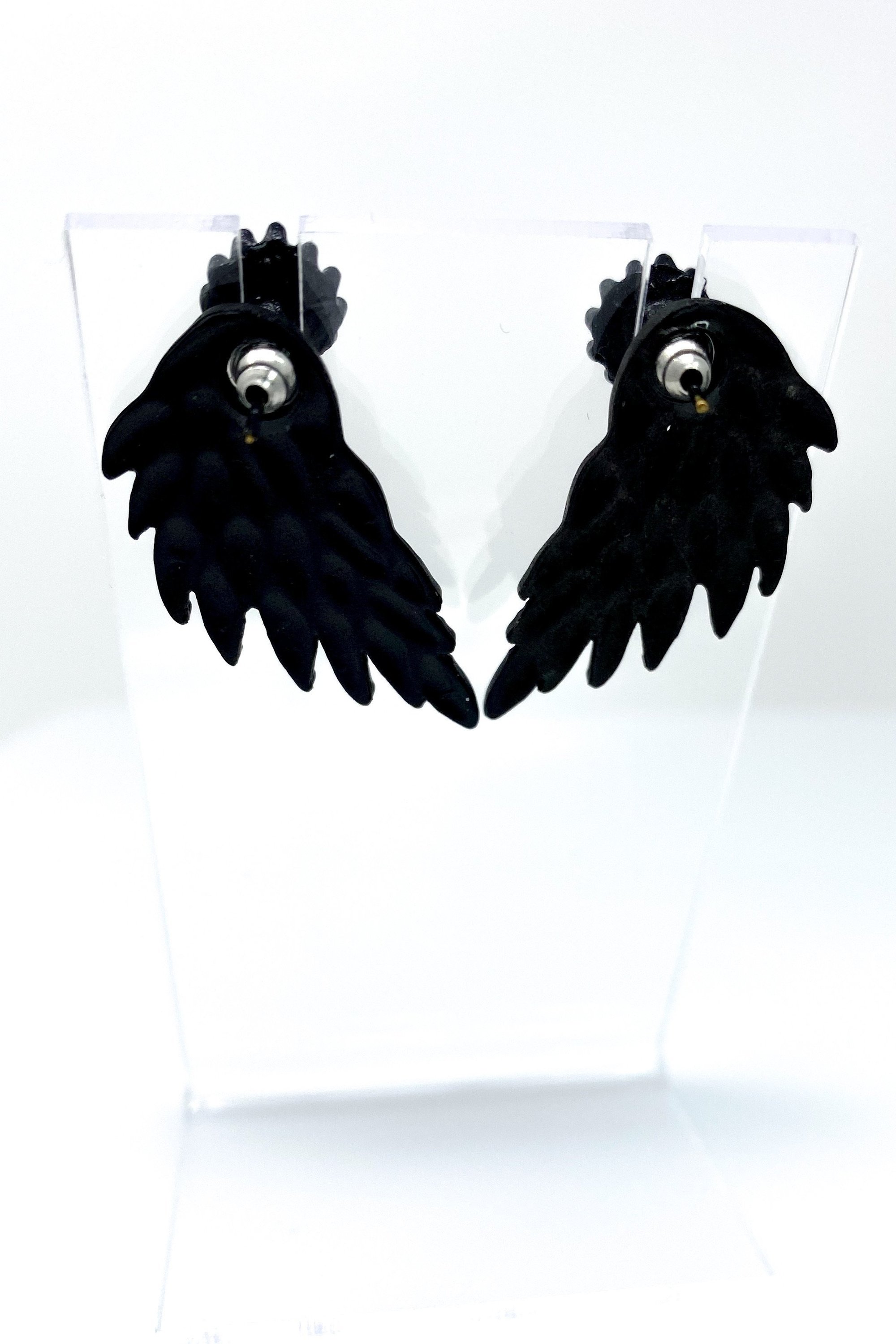 A pair of 420 Wingz Earrings featuring a unique wing design with a diamond accent, available in gold, silver, and black colors.