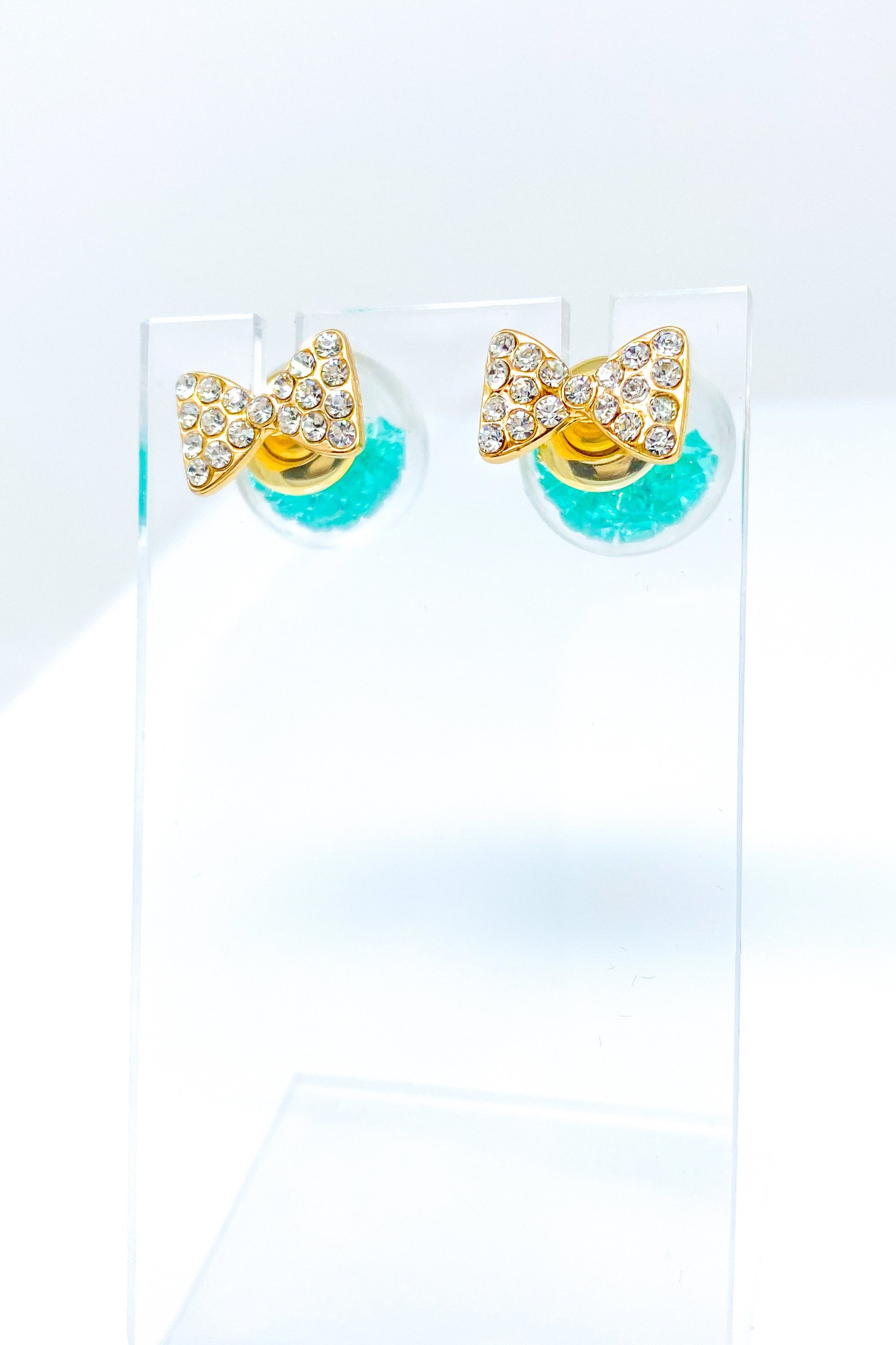 Bowtie Ice Studs featuring a sparkle bow tie design and moving ice ball, available in gold, blue, and green colors.