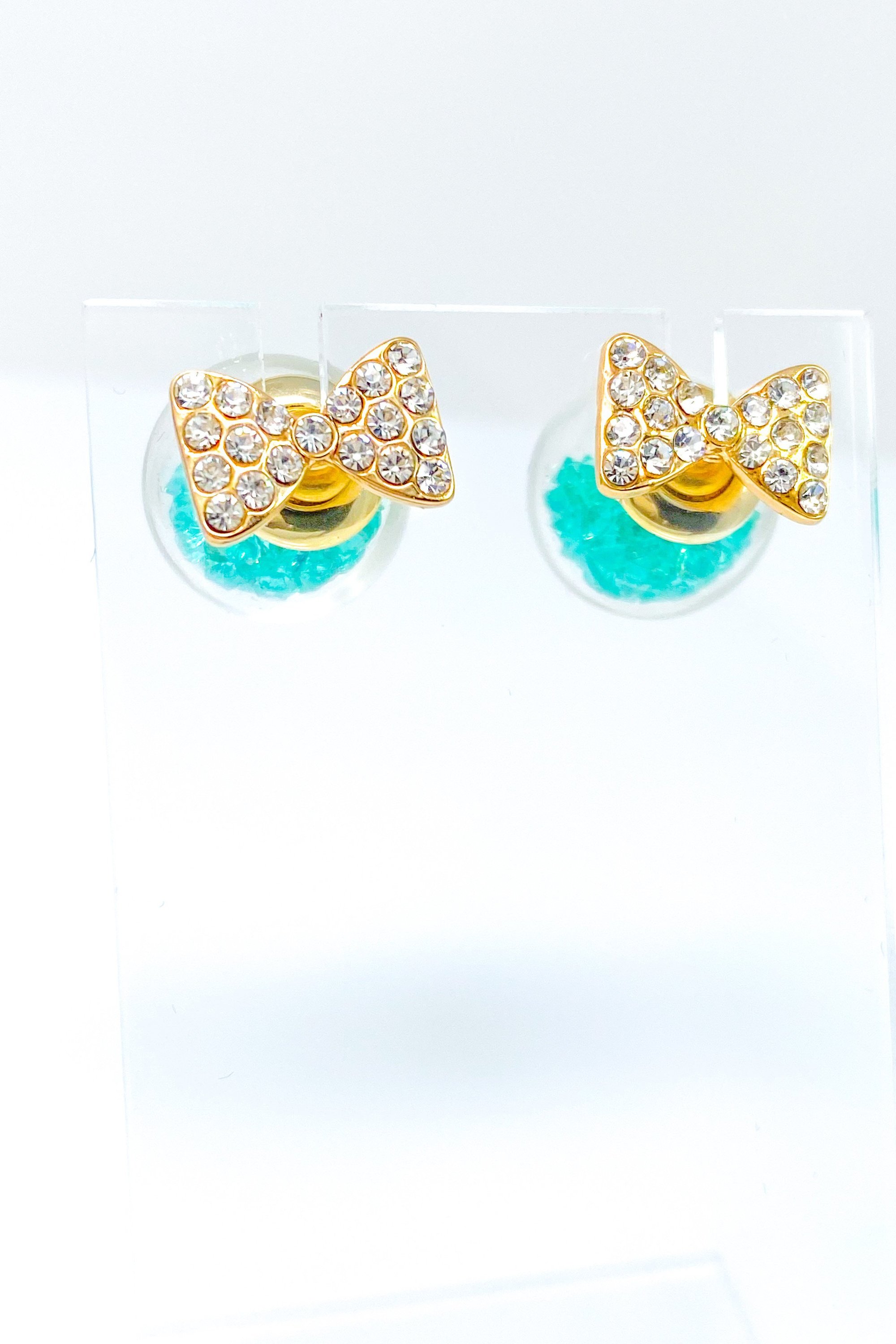 Bowtie Ice Studs featuring a sparkle bow tie design and moving ice ball, available in gold, blue, and green colors.