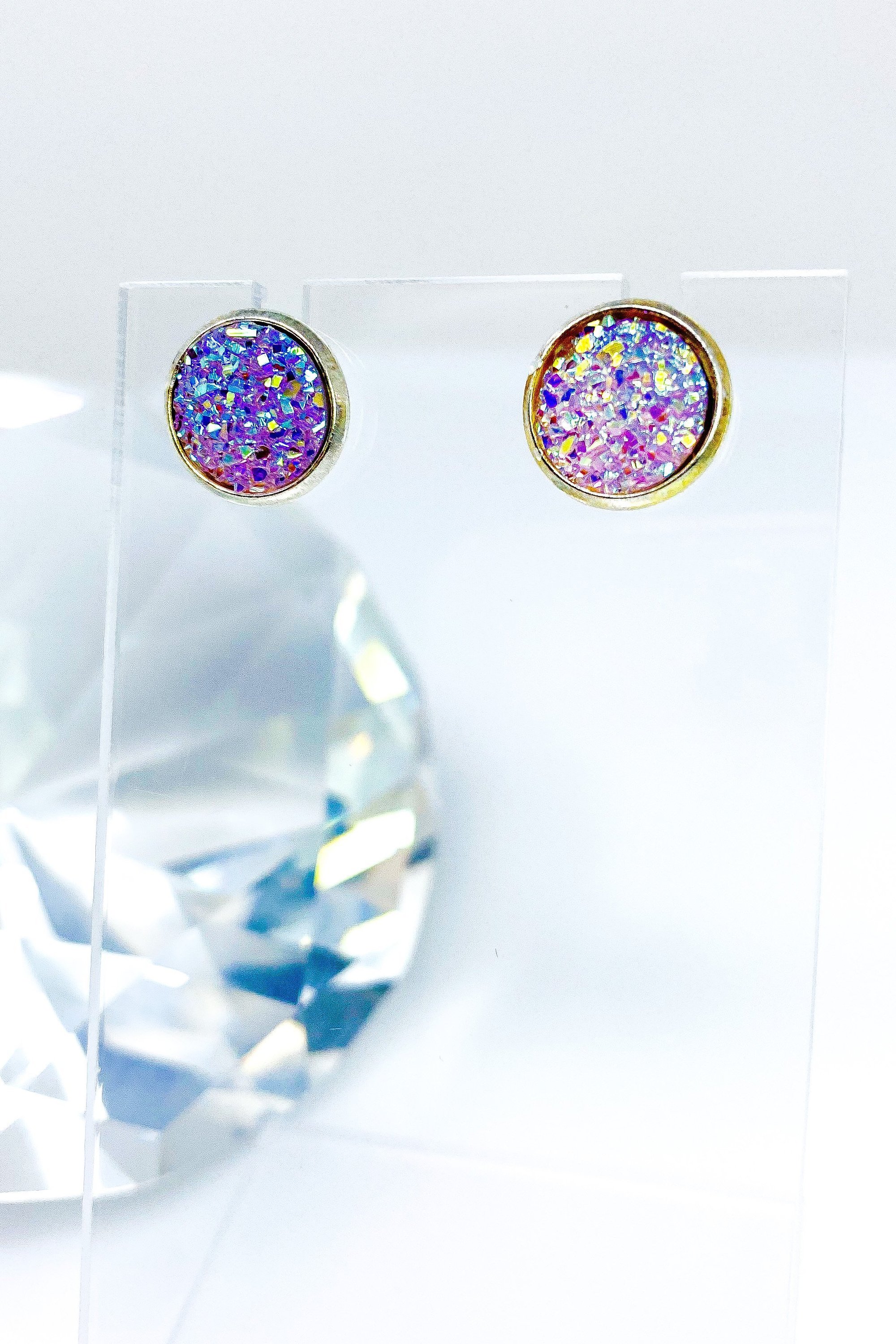 A pair of iridescent circular push back studs in vibrant colors, showcasing their geometric design and high-quality finish.