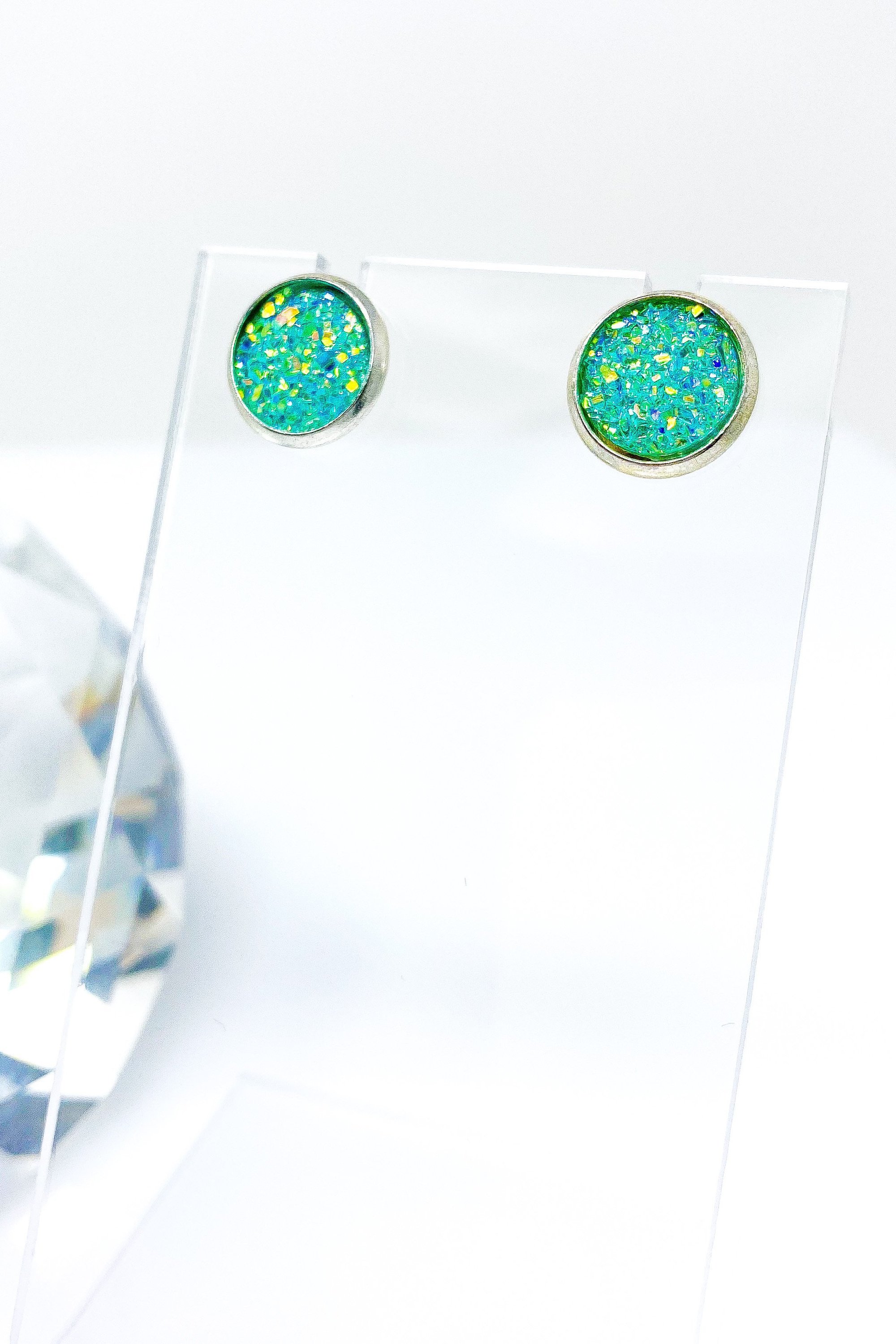 A pair of iridescent circular push back studs in vibrant colors, showcasing their geometric design and high-quality finish.