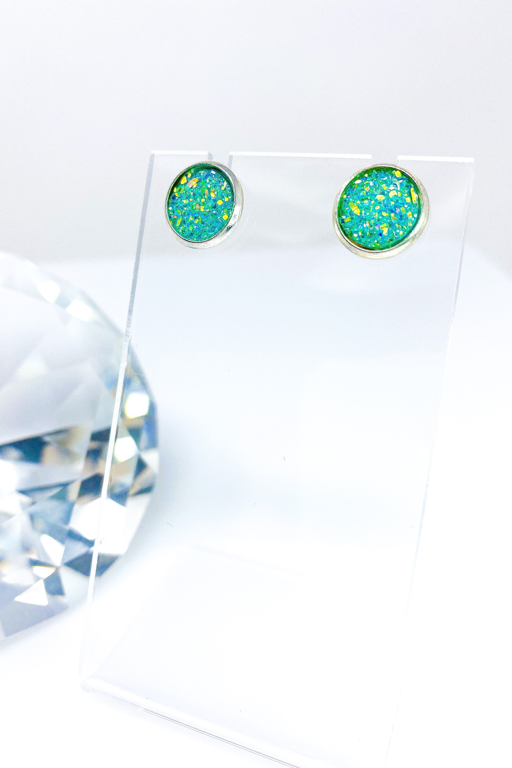 A pair of iridescent circular push back studs in vibrant colors, showcasing their geometric design and high-quality finish.