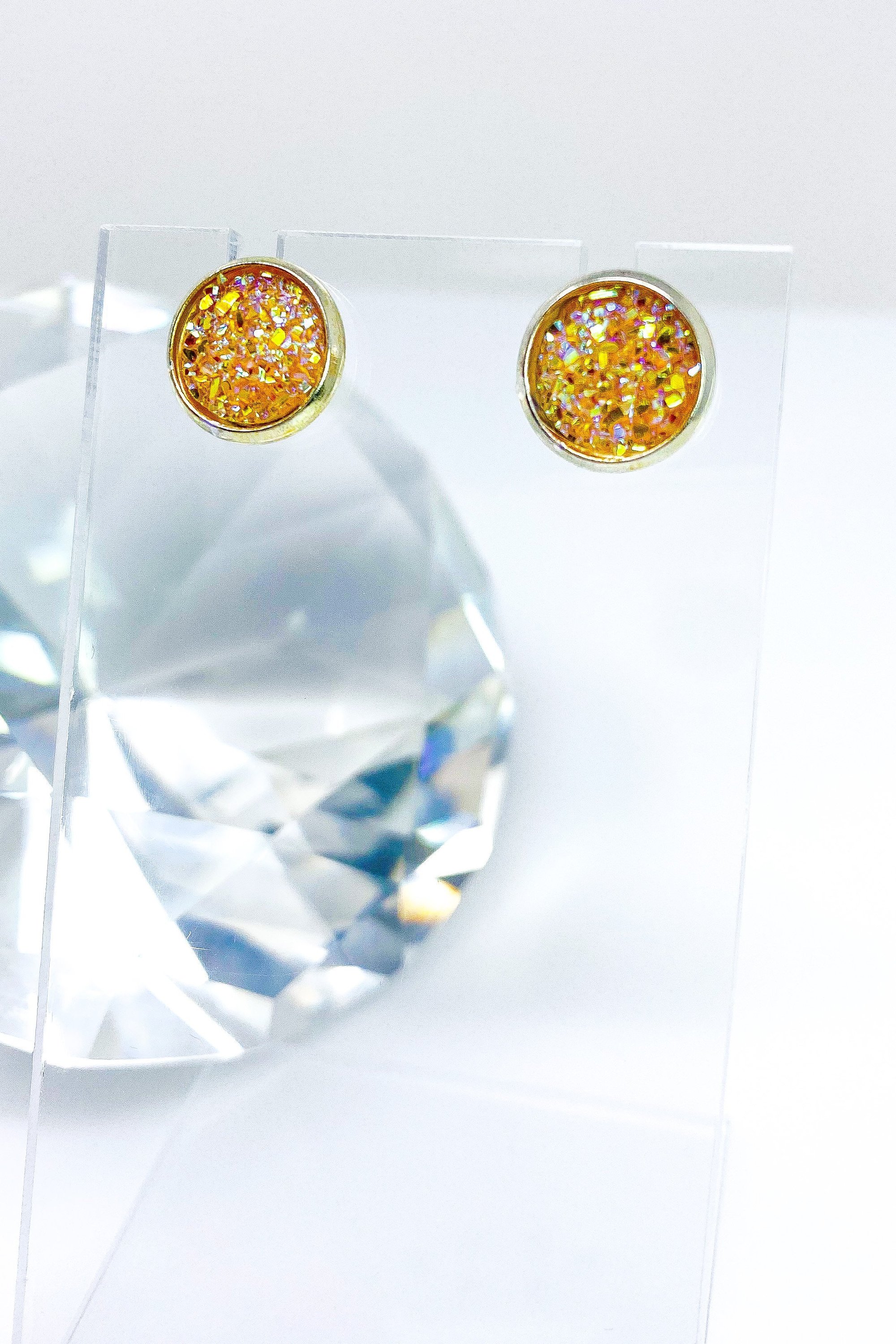 A pair of iridescent circular push back studs in vibrant colors, showcasing their geometric design and high-quality finish.