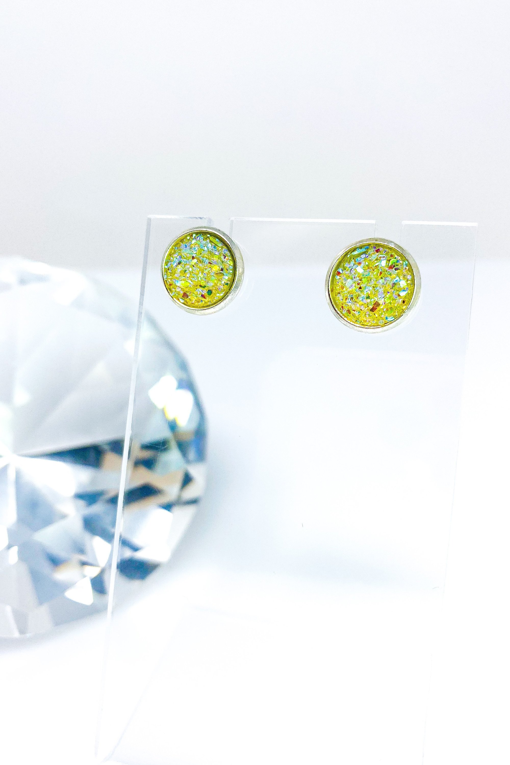 A pair of iridescent circular push back studs in vibrant colors, showcasing their geometric design and high-quality finish.