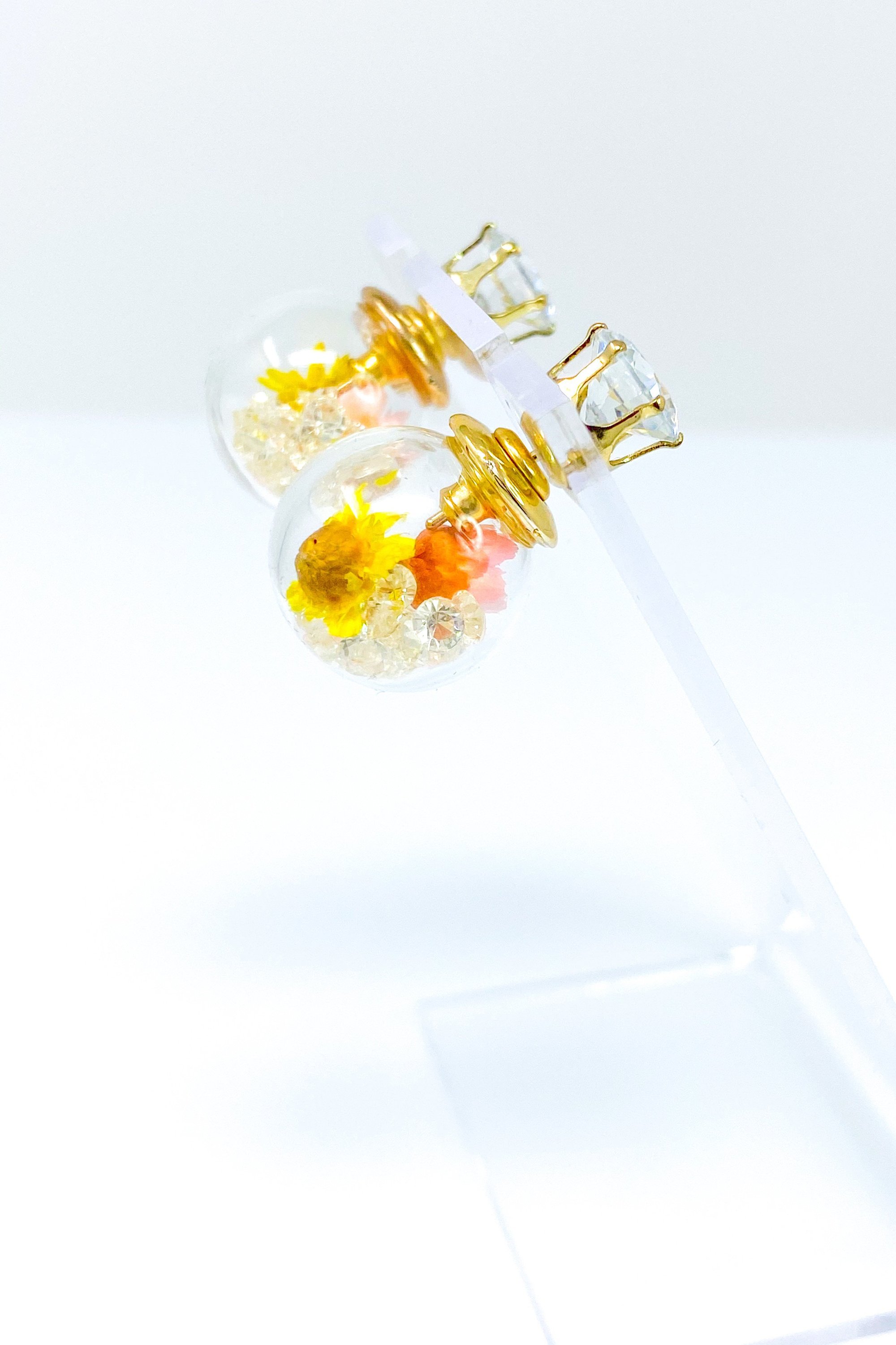 Perennial Ice Studs featuring handcrafted moving flowers and a plastique ice ball design in gold and multicolored options.