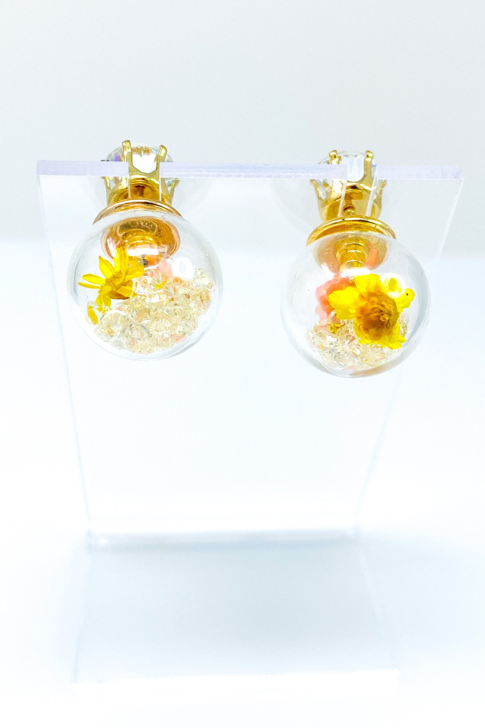 Perennial Ice Studs featuring handcrafted moving flowers and a plastique ice ball design in gold and multicolored options.