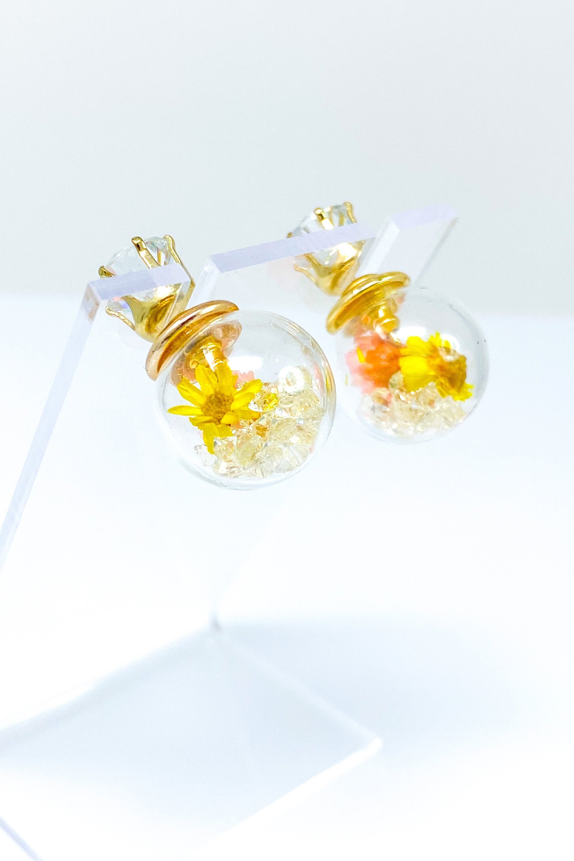 Perennial Ice Studs featuring handcrafted moving flowers and a plastique ice ball design in gold and multicolored options.