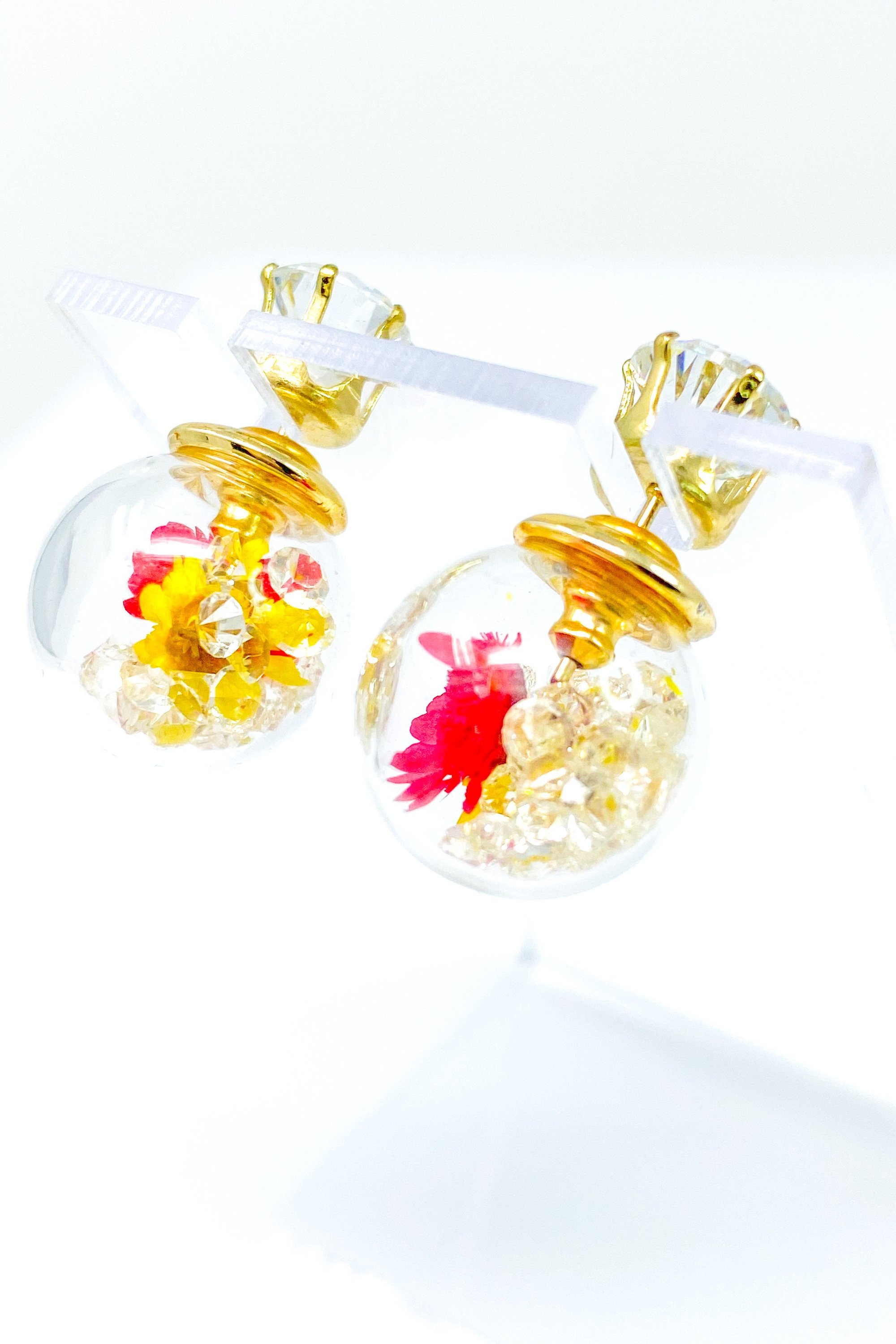 Perennial Ice Studs featuring handcrafted moving flowers and a plastique ice ball design in gold and multicolored options.