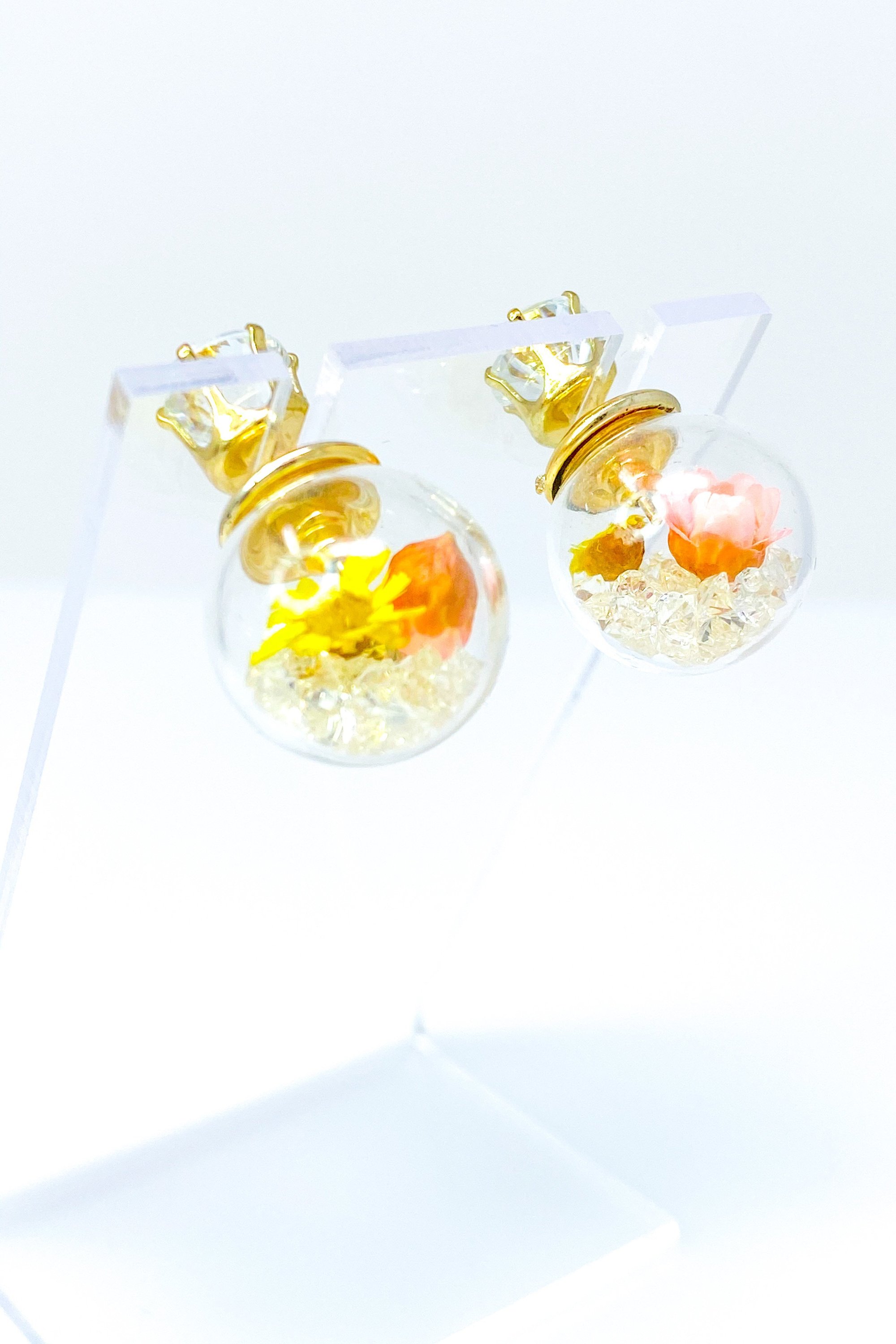 Perennial Ice Studs featuring handcrafted moving flowers and a plastique ice ball design in gold and multicolored options.