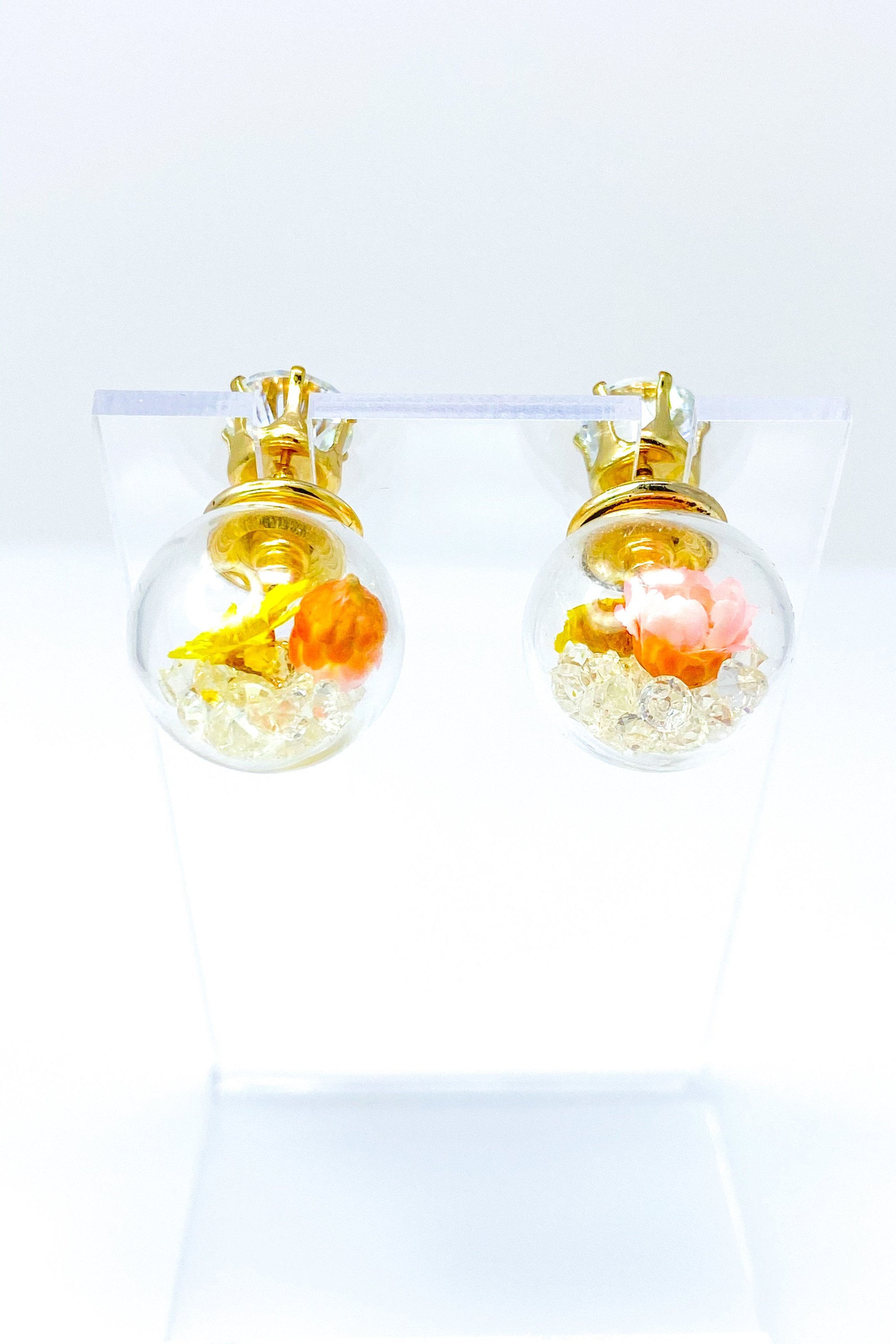 Perennial Ice Studs featuring handcrafted moving flowers and a plastique ice ball design in gold and multicolored options.