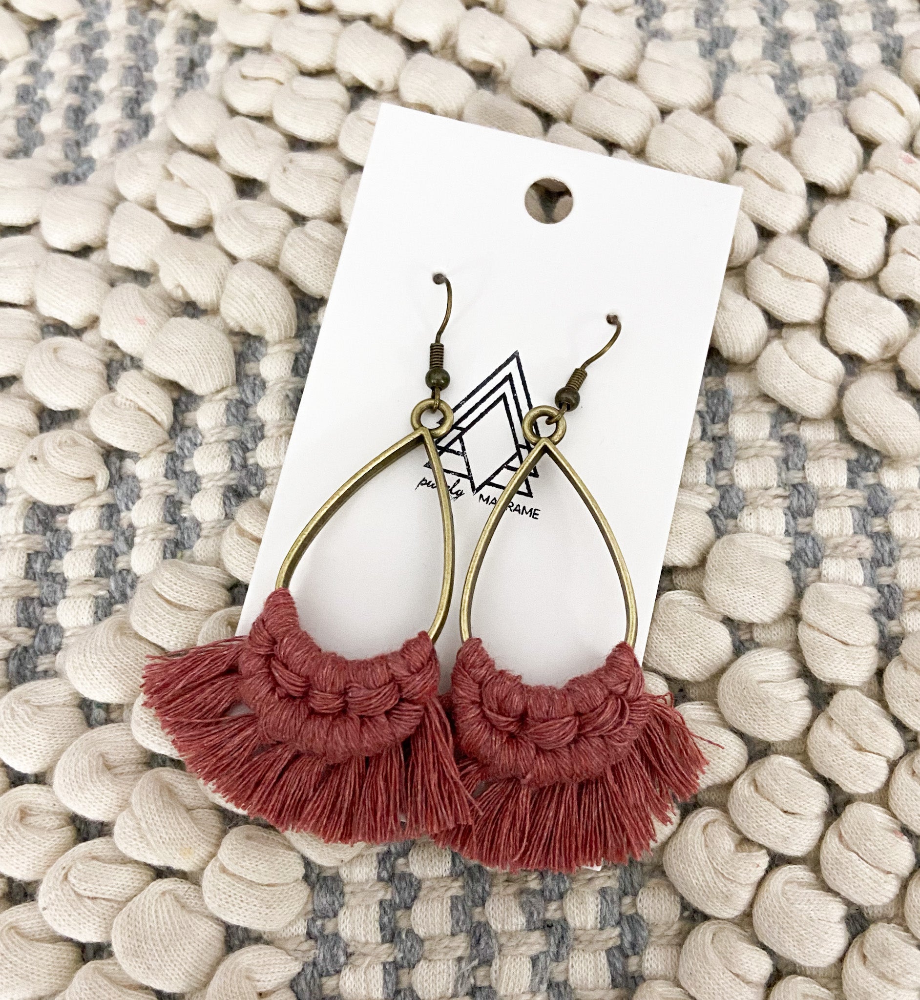 A pair of lightweight terracotta teardrop accessories made from 100% natural cotton, showcasing their elegant shape and color.