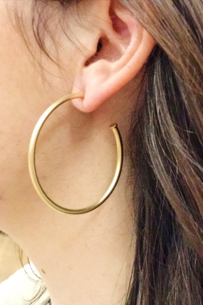 A pair of elegant matte gold hoop earrings with a 2-inch radius, showcasing a modern and stylish design.