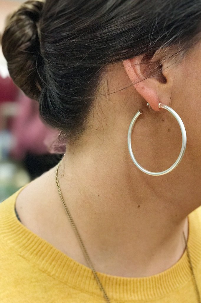 A pair of elegant matte silver hoop earrings with a 2-inch radius, showcasing a stylish and modern design.