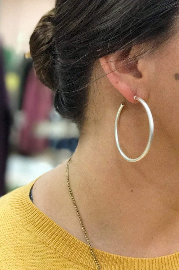 A pair of elegant matte silver hoop earrings with a 2-inch radius, showcasing a stylish and modern design.