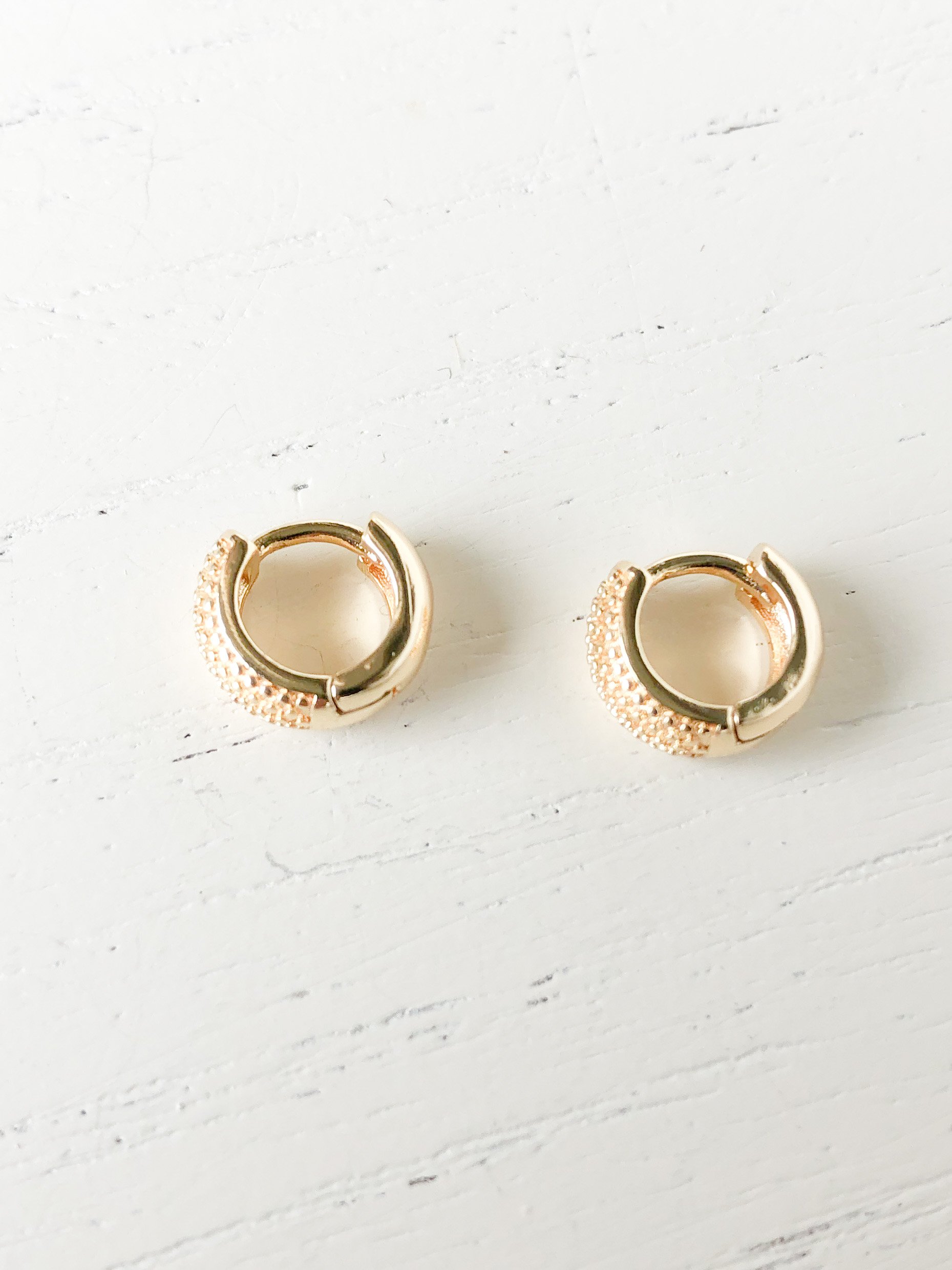 A pair of gold filled textured huggie earrings, measuring 10mm, showcasing a stylish and modern design.