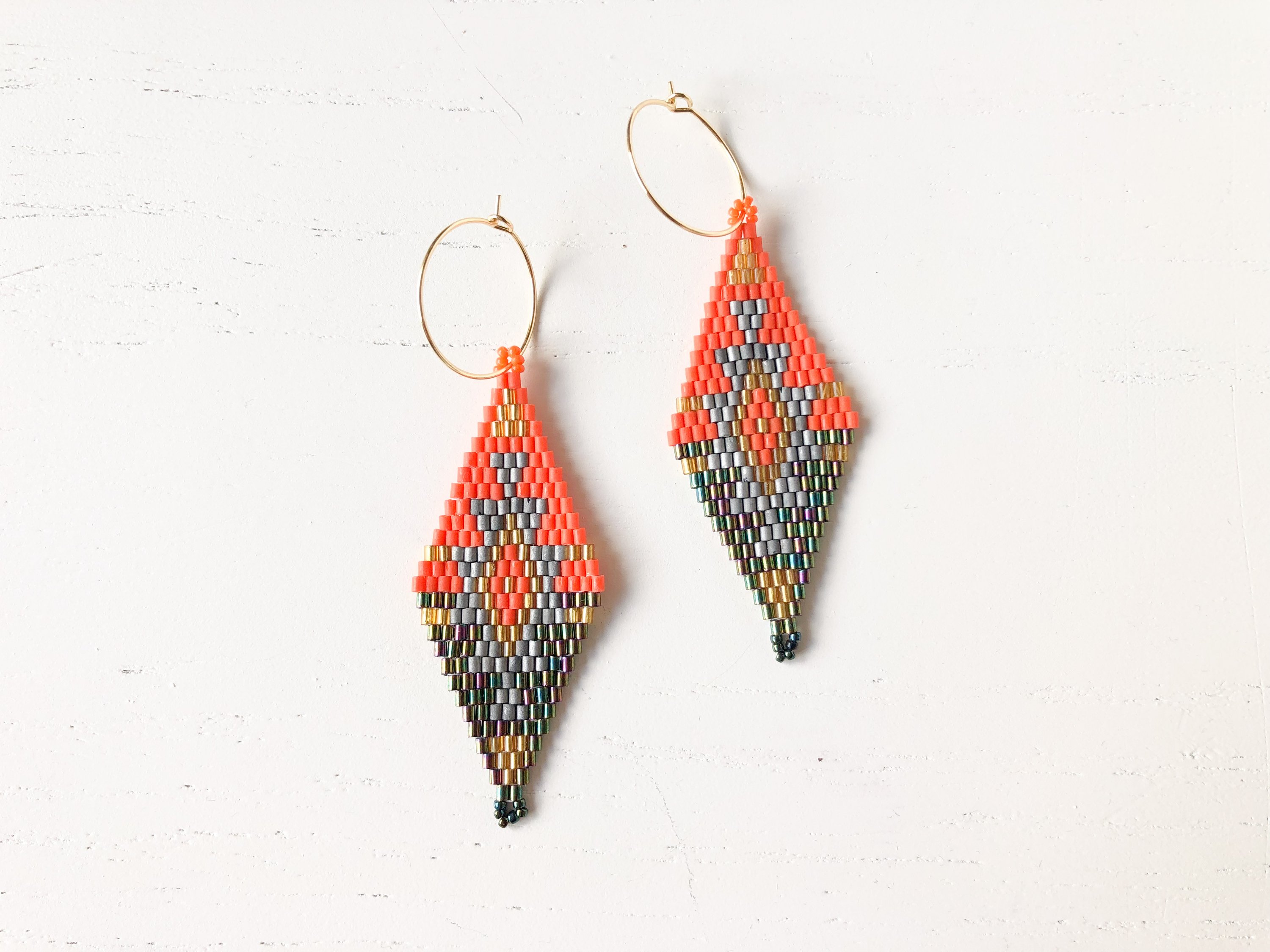 The Vera - Green/Orange, a hand-beaded accessory made from nickel-free brass, showcasing vibrant green and orange colors.