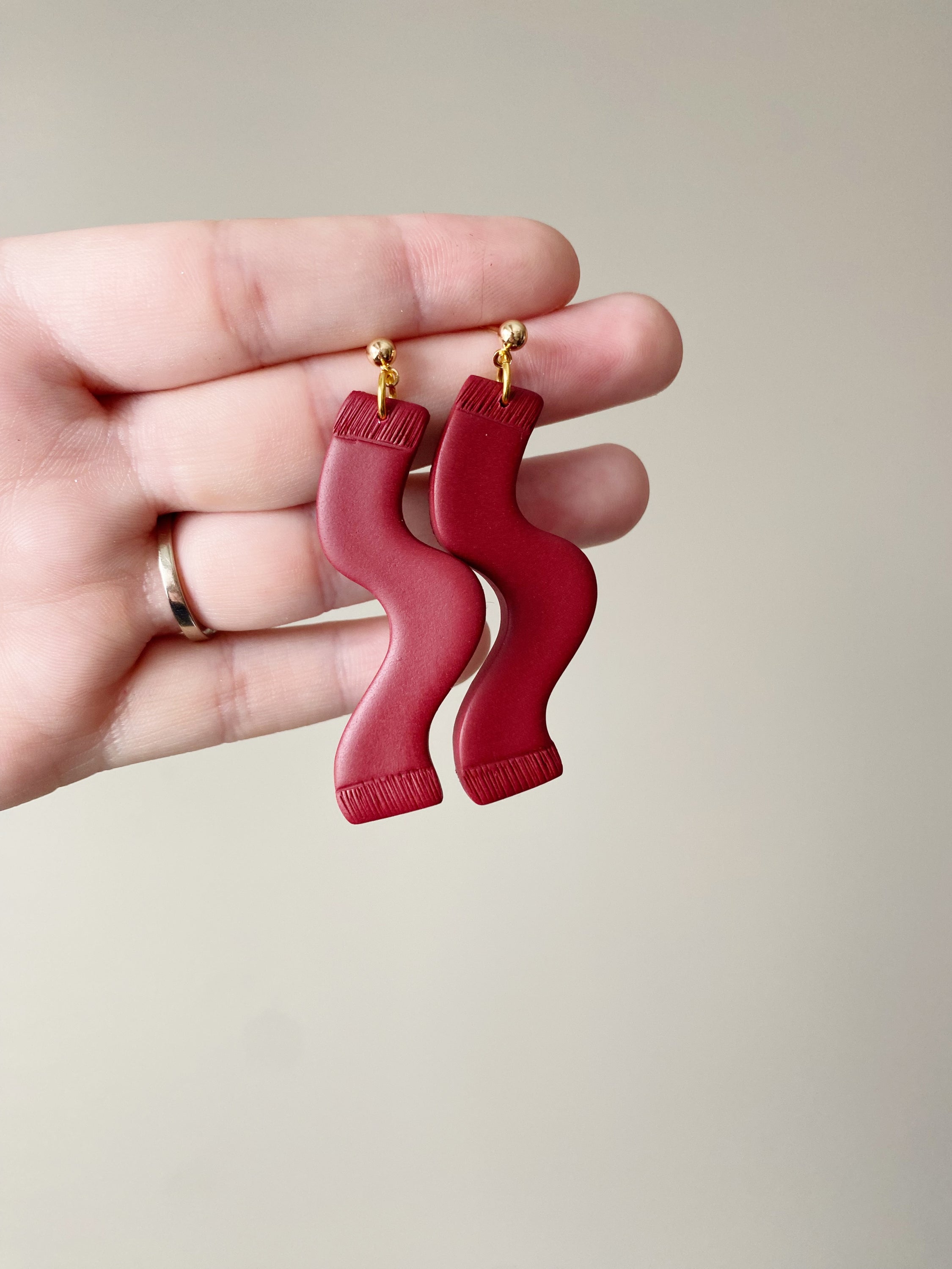 A pair of handmade red polymer clay earrings inspired by TS, featuring unique designs and hypoallergenic posts, perfect for any occasion.