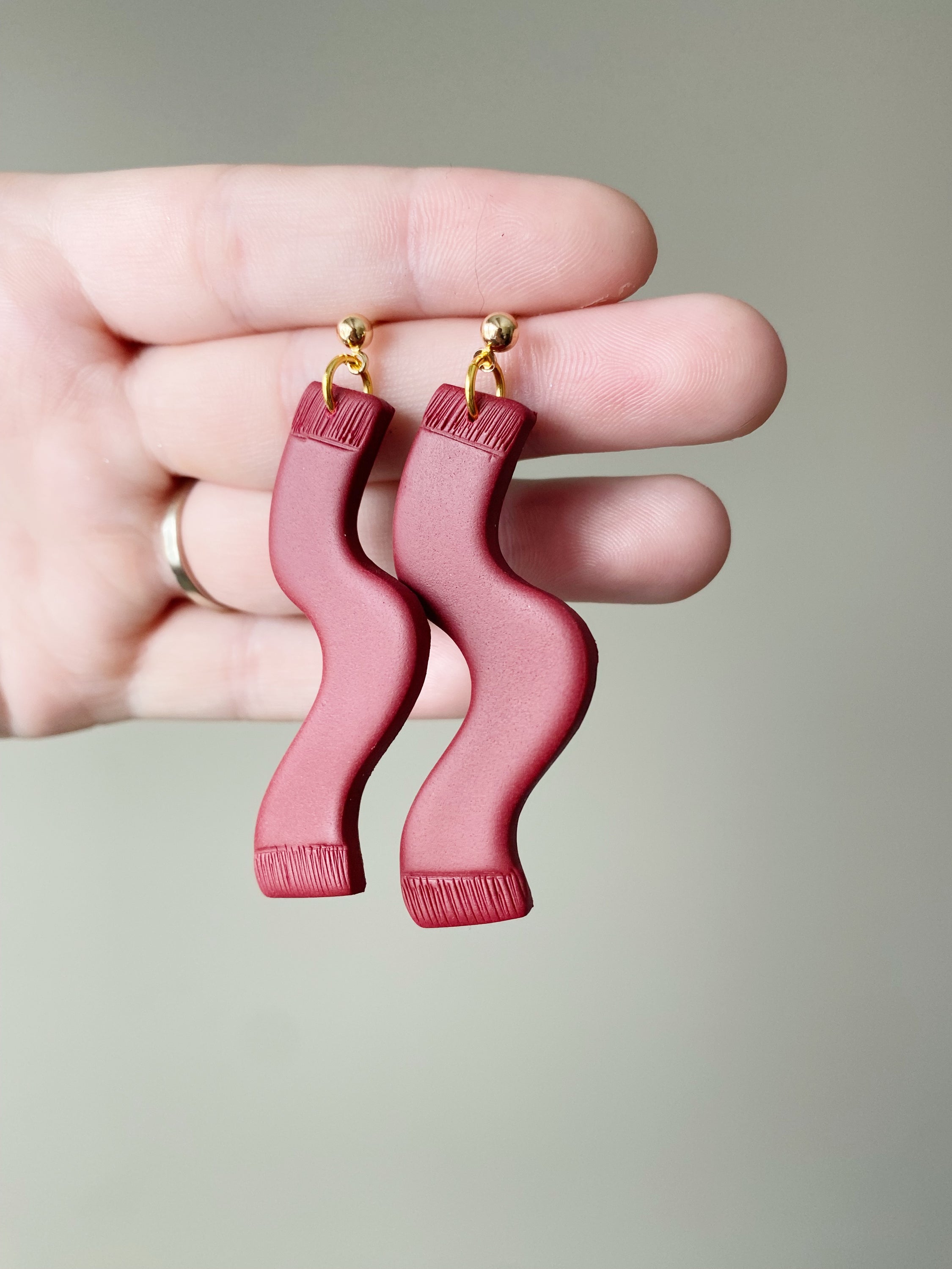 A pair of handmade red polymer clay earrings inspired by TS, featuring unique designs and hypoallergenic posts, perfect for any occasion.