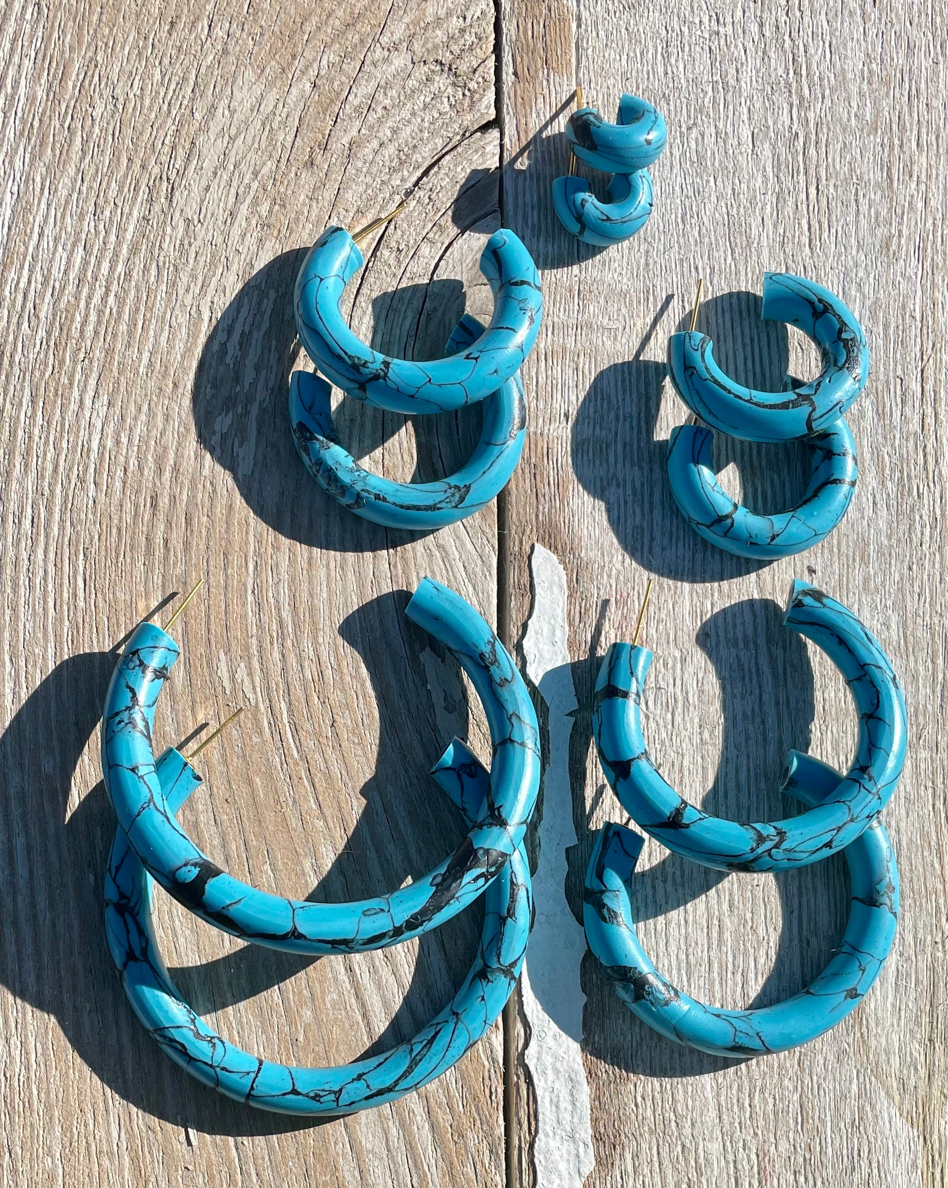 Handmade turquoise hoop earrings with unique patterns and stainless steel hooks, showcasing vibrant color and artisanal craftsmanship.