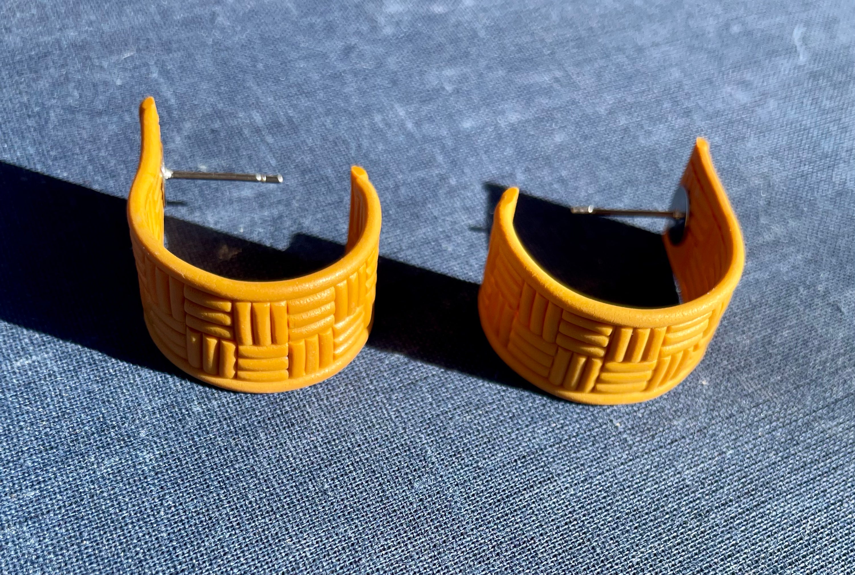 A pair of handmade yellow checked huggie earrings featuring a vibrant check pattern, lightweight design, and stainless steel hooks.