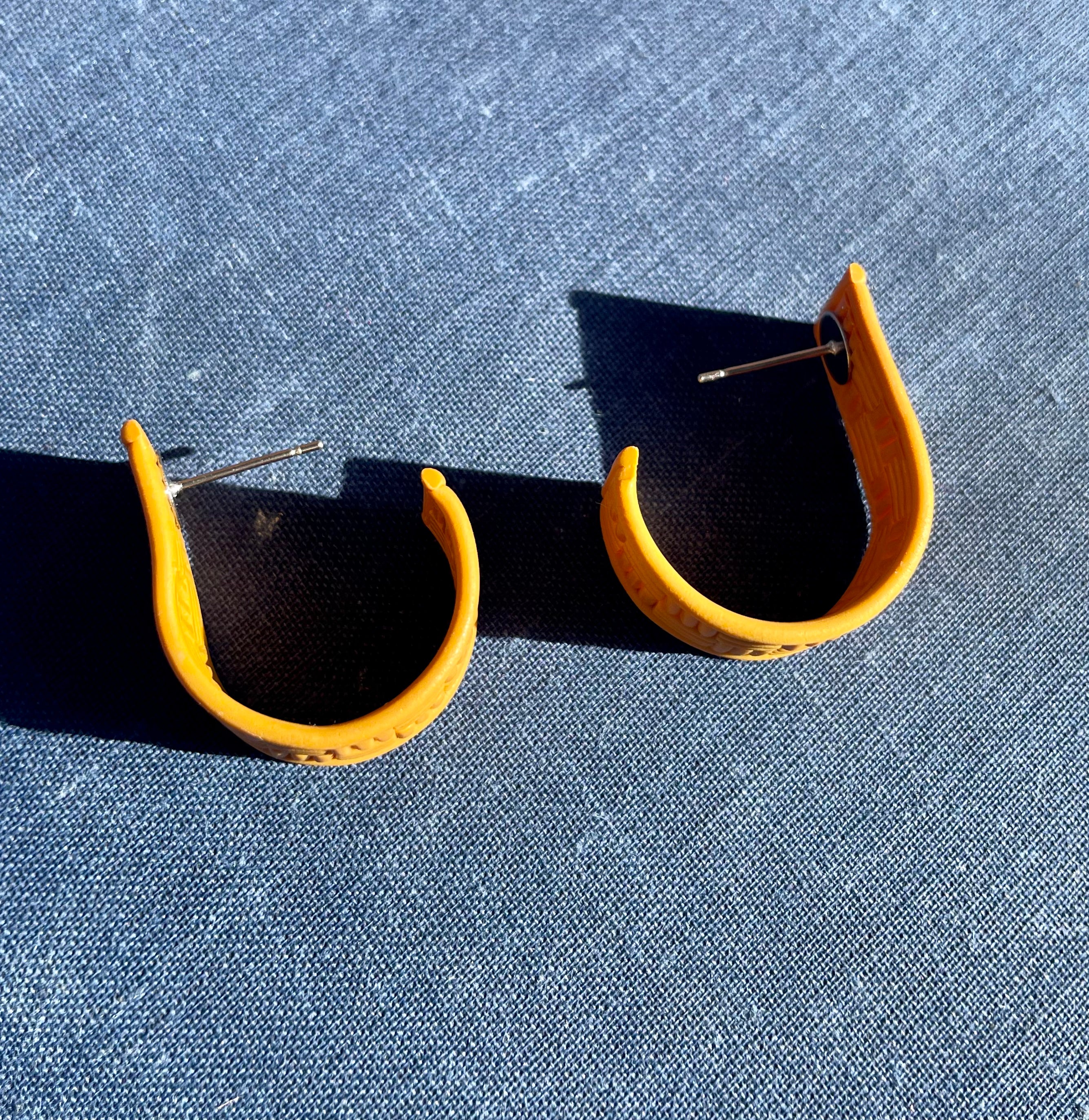 A pair of handmade yellow checked huggie earrings featuring a vibrant check pattern, lightweight design, and stainless steel hooks.