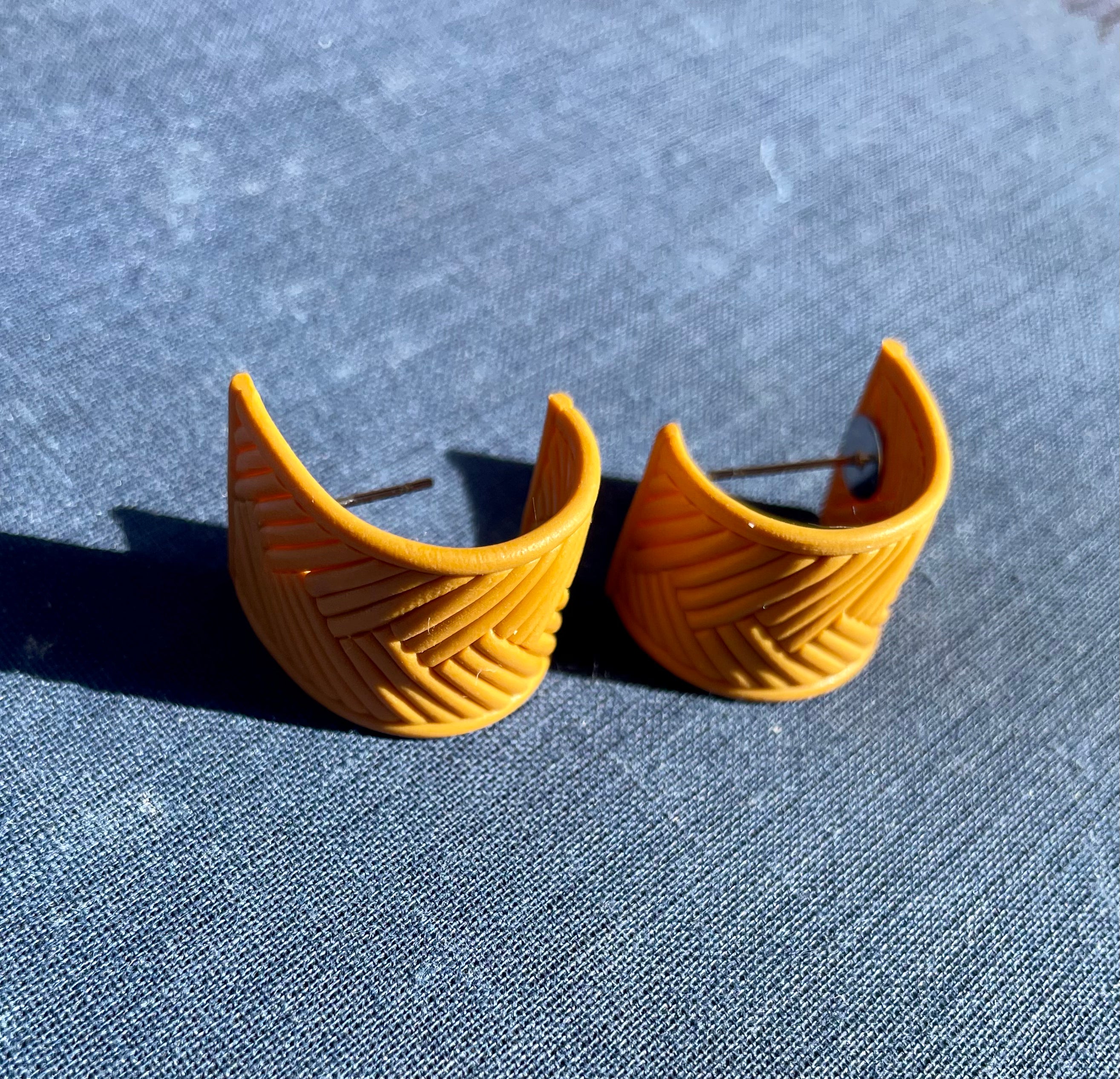 A pair of handmade yellow chevron huggie earrings, showcasing a vibrant chevron pattern, lightweight design, and stainless steel hooks.