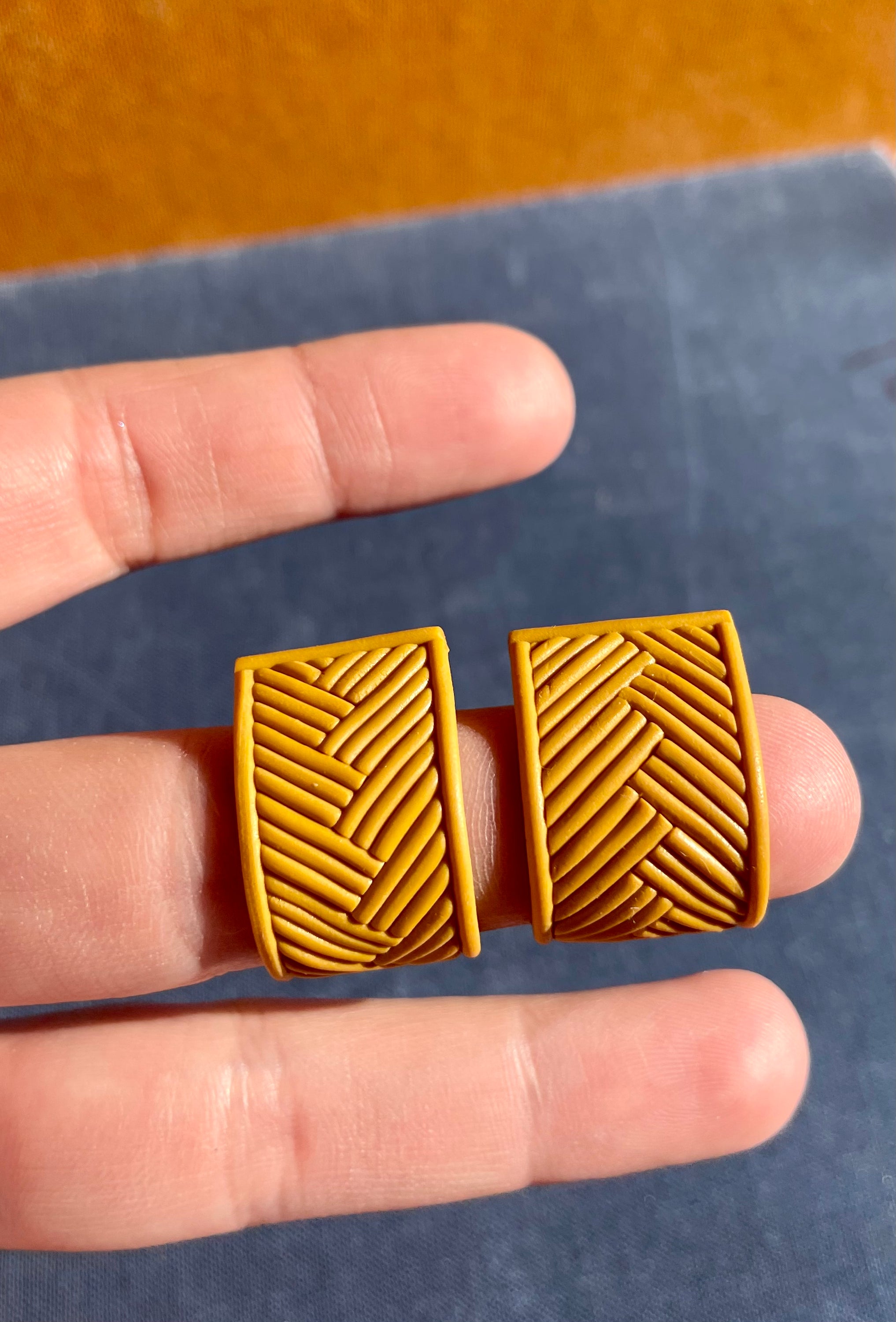 A pair of handmade yellow chevron huggie earrings, showcasing a vibrant chevron pattern, lightweight design, and stainless steel hooks.