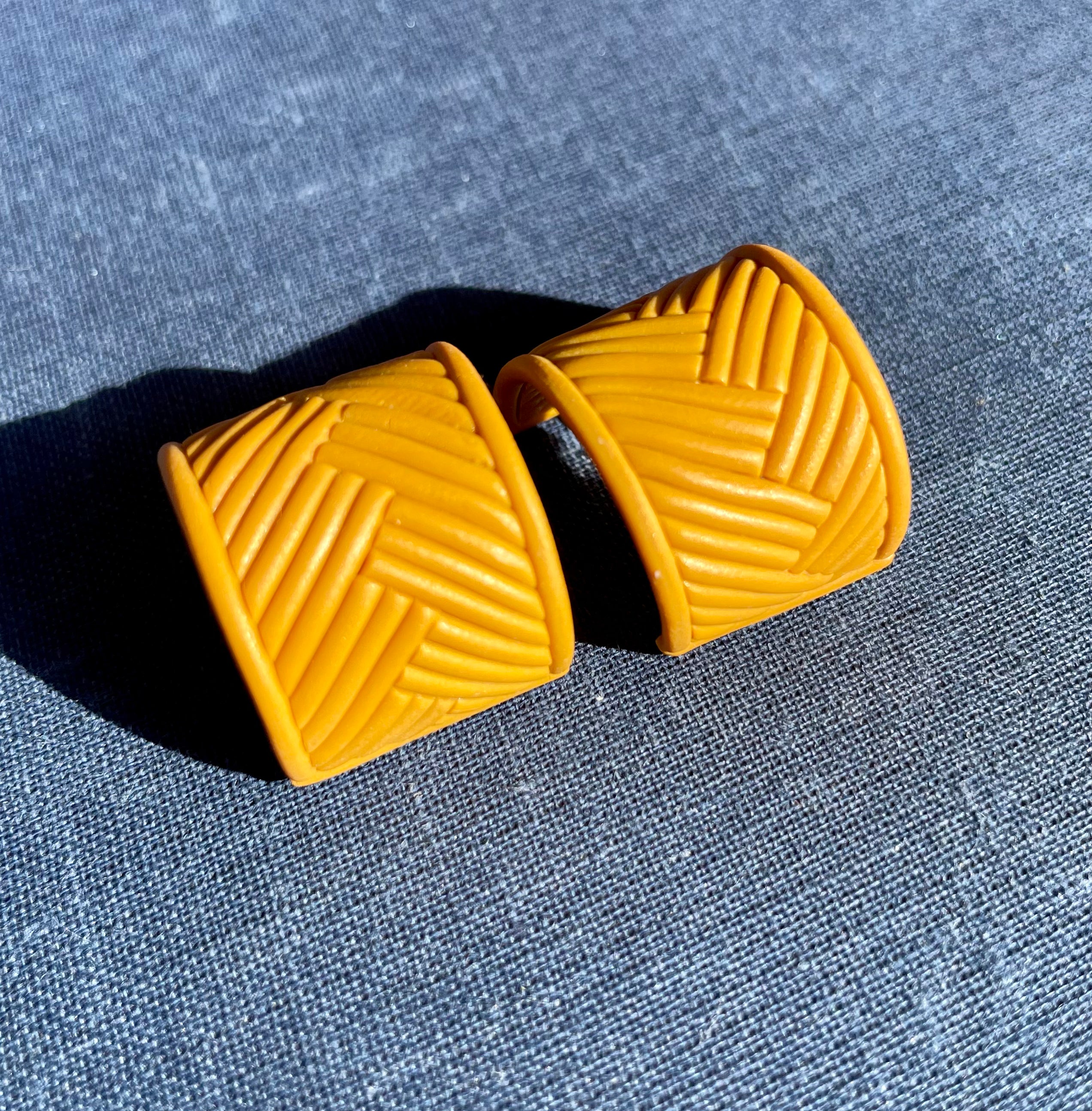 A pair of handmade yellow chevron huggie earrings, showcasing a vibrant chevron pattern, lightweight design, and stainless steel hooks.