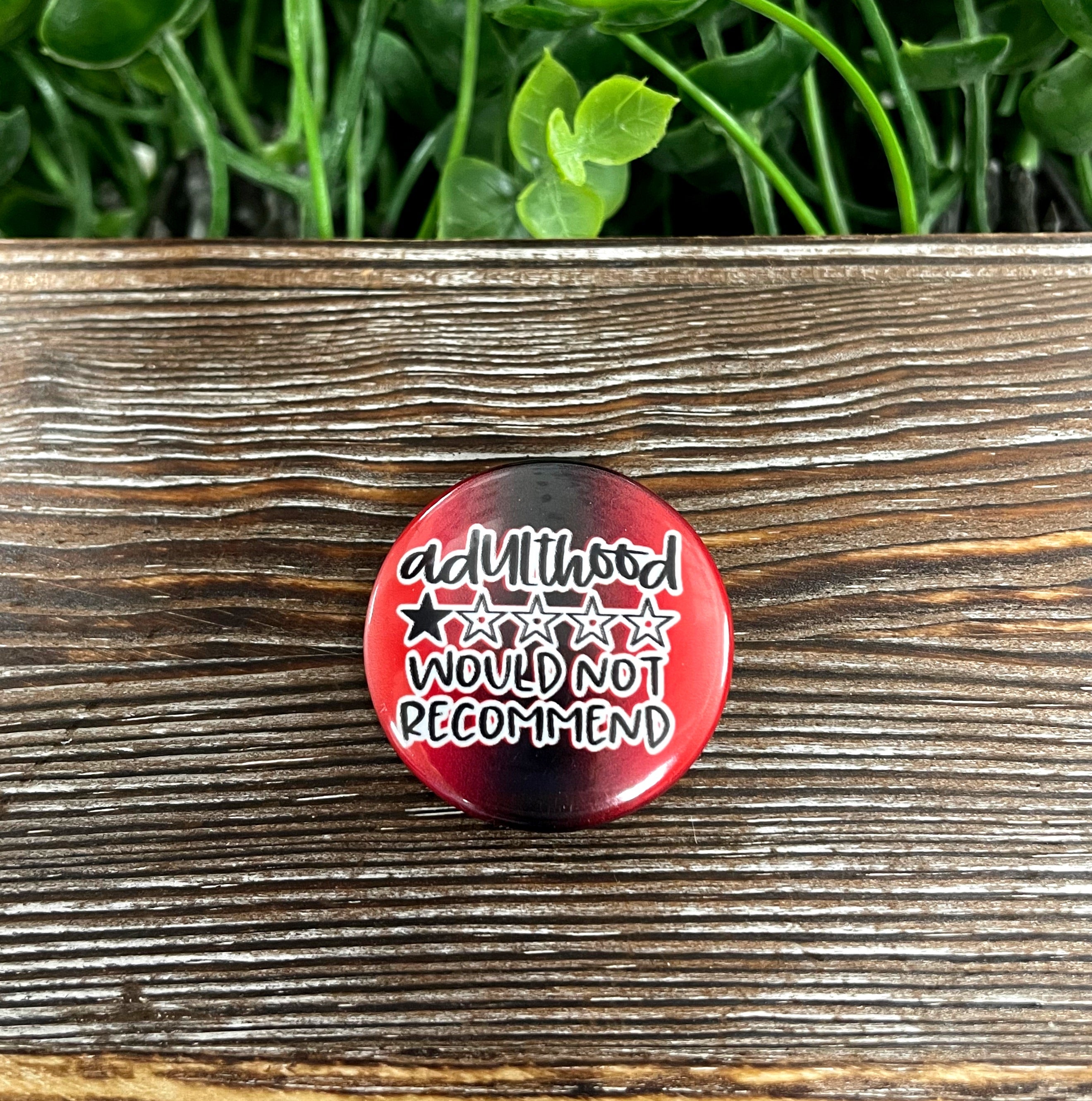 Adulthood Would Not Recommend graphic art button in vibrant red, measuring 1.25 inches, showcasing a fun design.