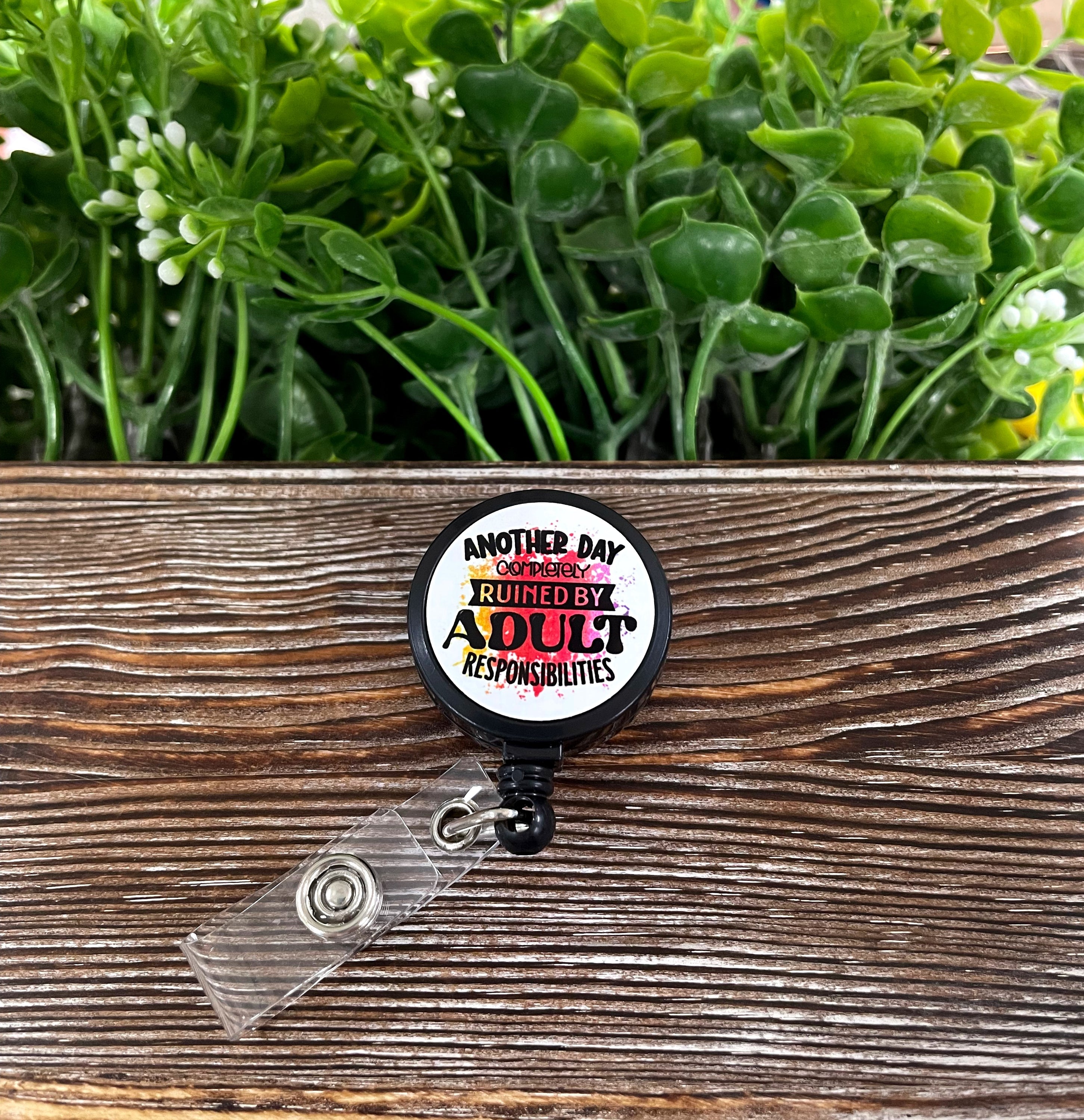 Retractable badge reel with a humorous design about adult responsibilities, featuring a metal blank and plastic reel.