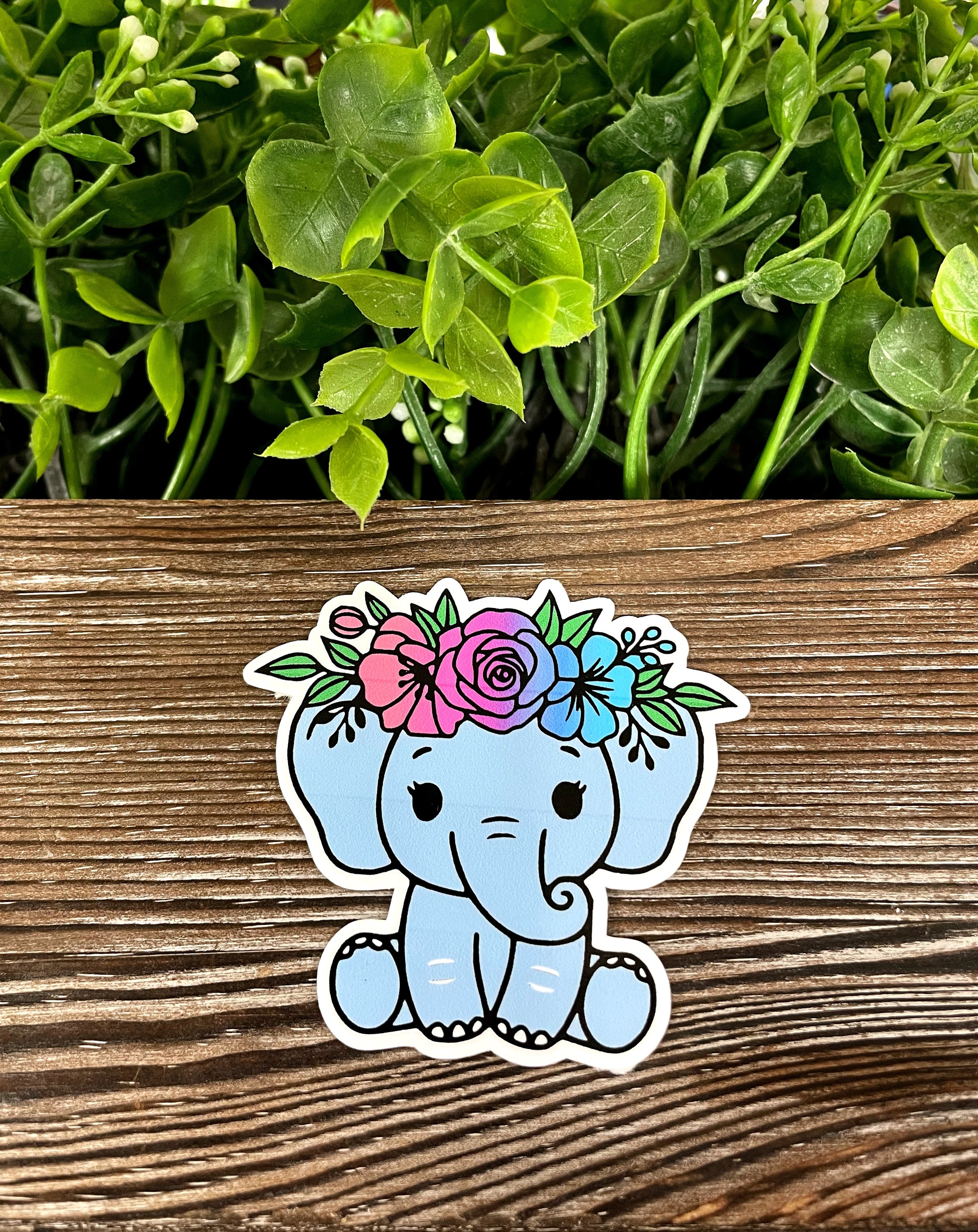 A vibrant baby blue elephant sticker with a flower crown, showcasing intricate details and a whimsical design, perfect for personalizing various surfaces.