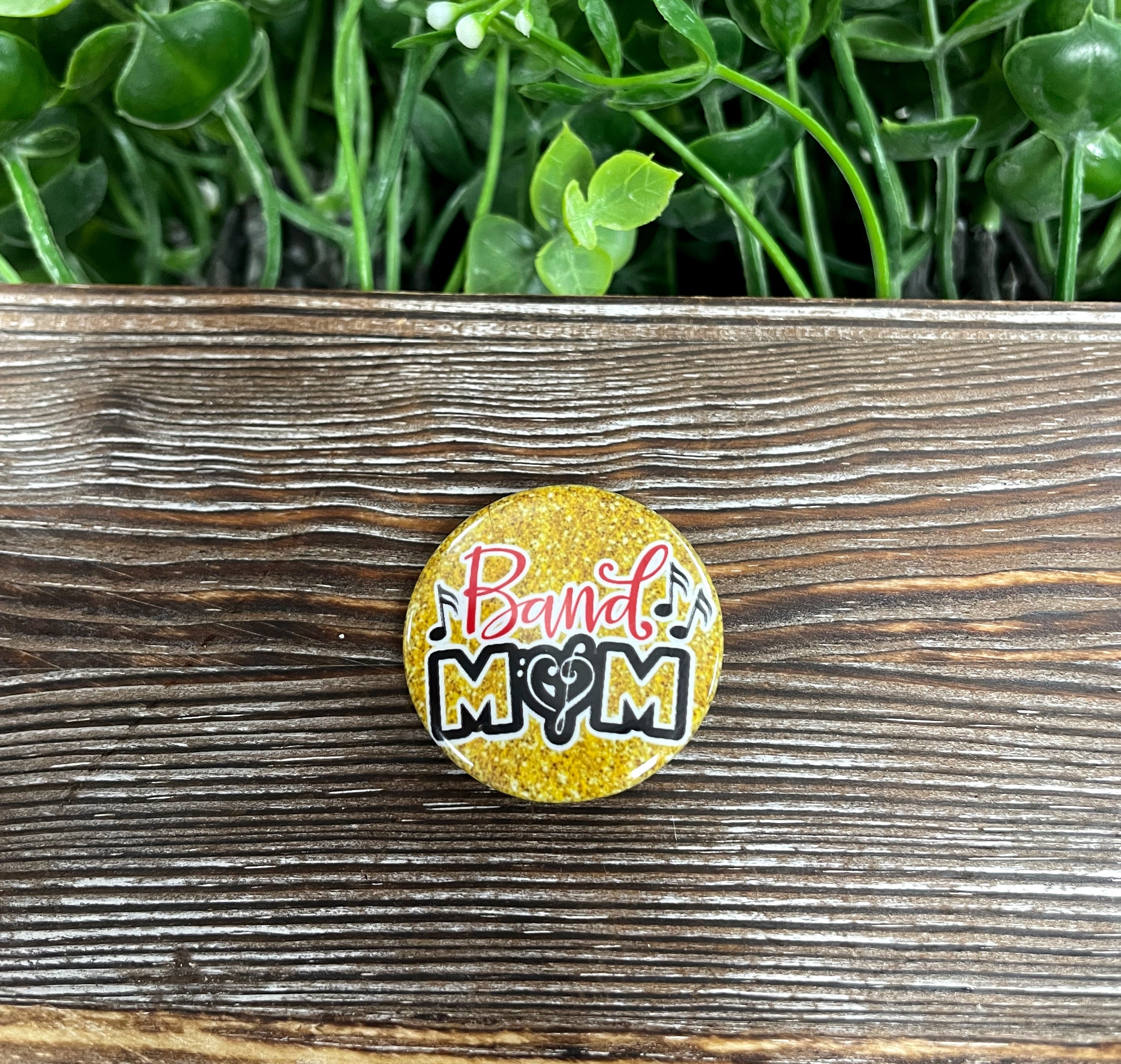 Band Mom graphic art button with a gold glitter background, measuring 1.25 inches, perfect for accessories.