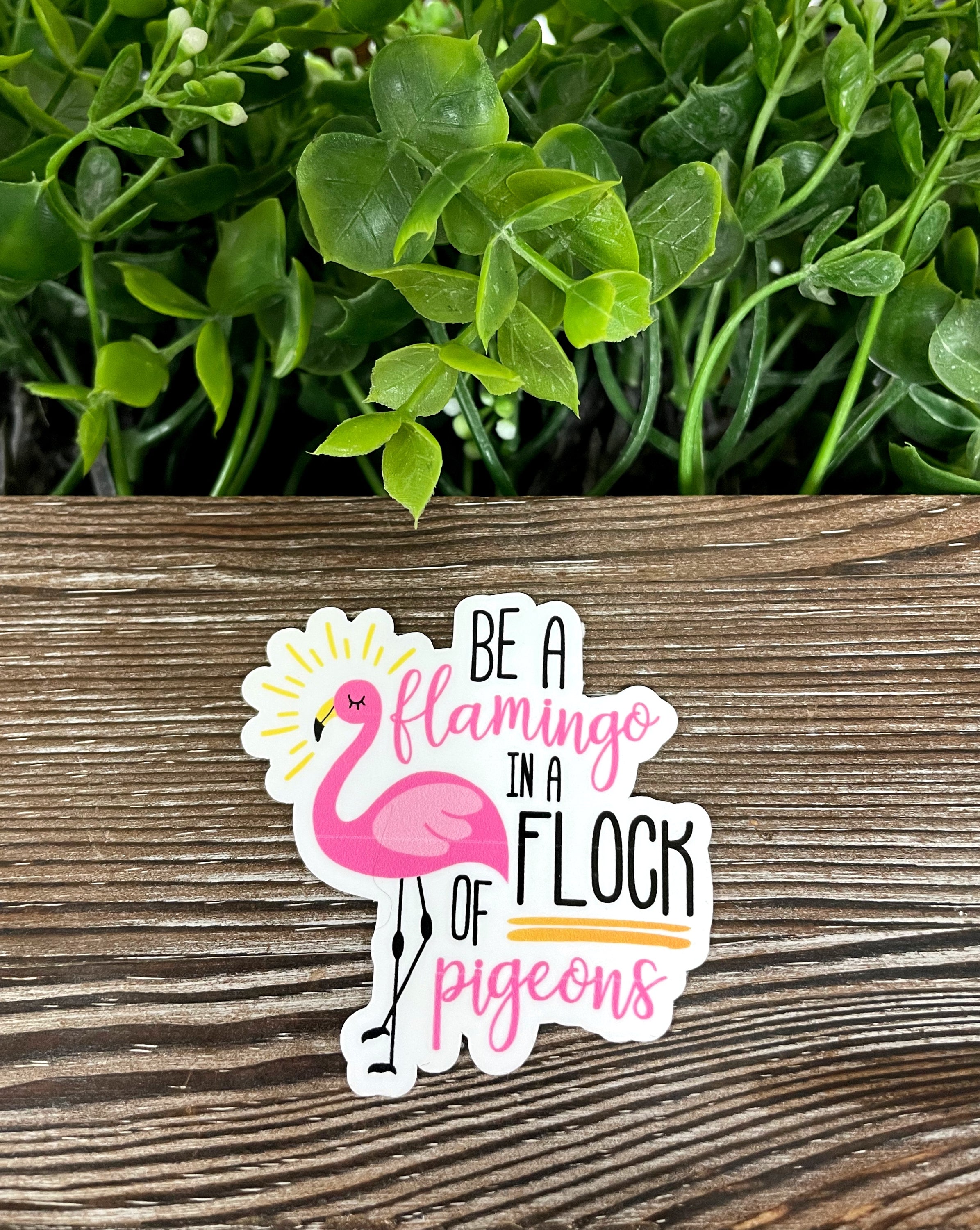 Colorful Be a Flamingo in a Flock of Pigeons sticker on a smooth surface, showcasing vibrant design and die cut shape.