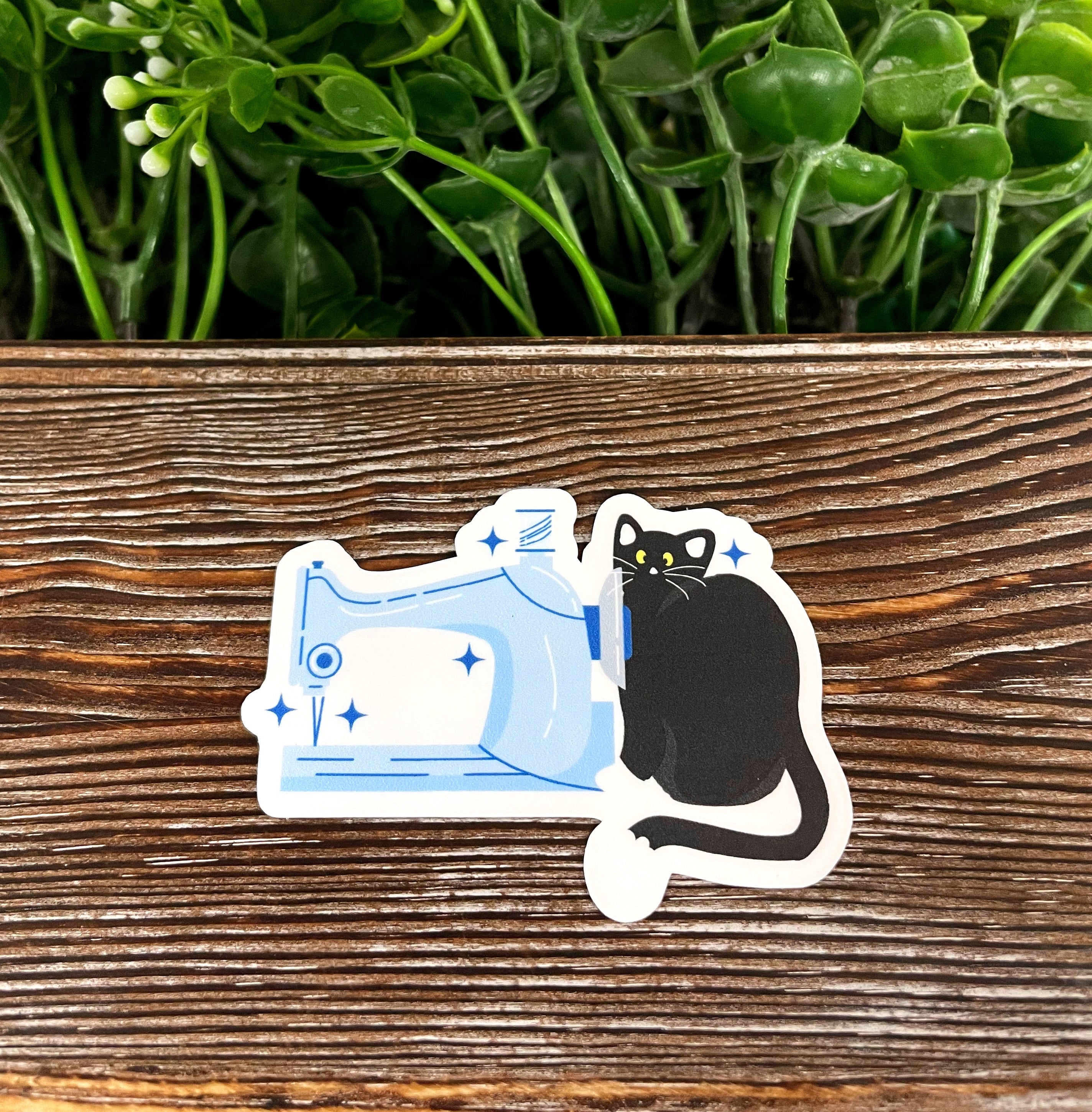 A die cut vinyl sticker featuring a black cat and a sewing machine, showcasing a boho fun design, perfect for personalizing items.