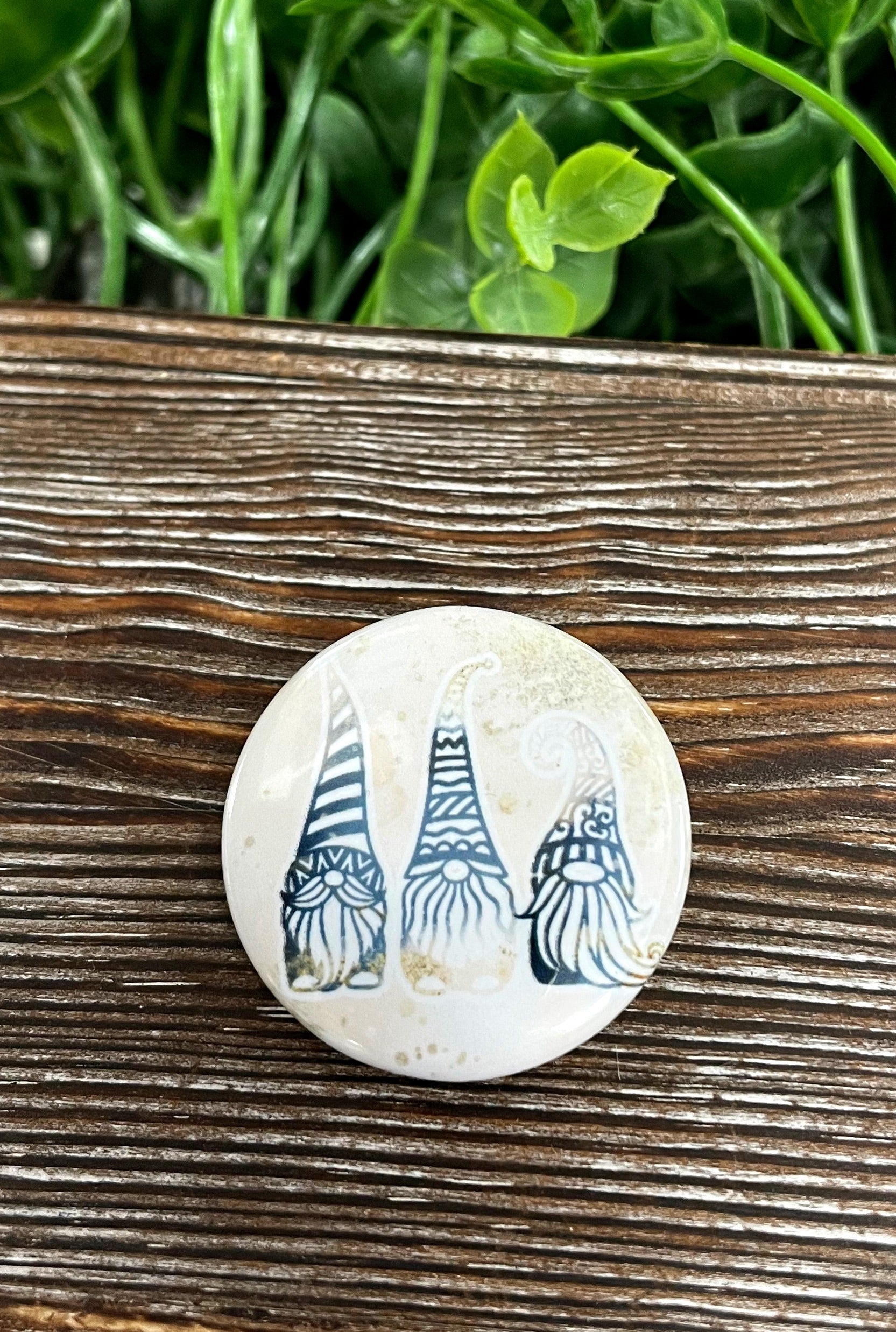 A vibrant 1.25-inch button pin featuring blue and gold glitter gnomes, perfect for personalizing bags and accessories.