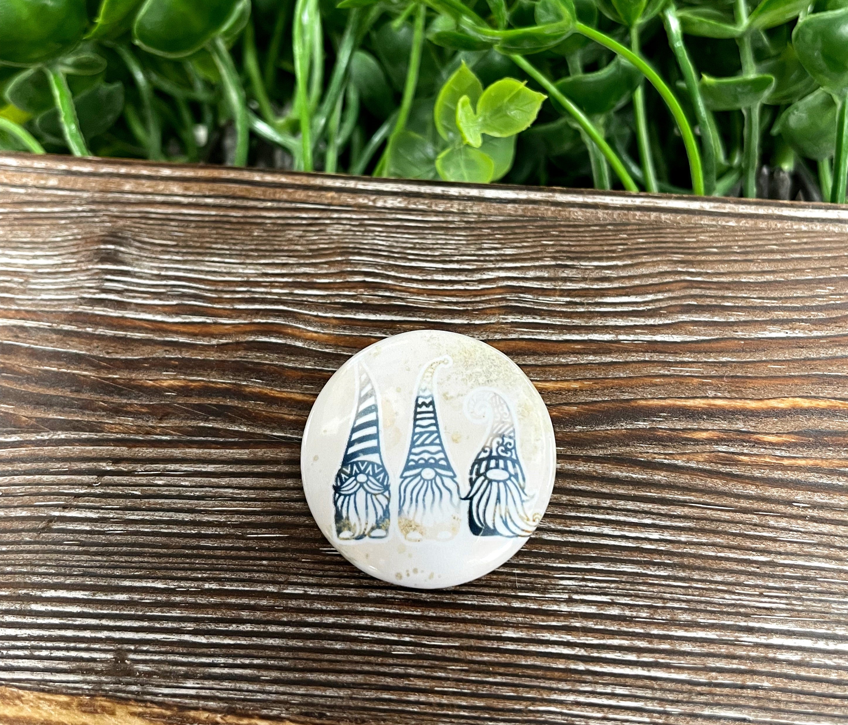 A vibrant 1.25-inch button pin featuring blue and gold glitter gnomes, perfect for personalizing bags and accessories.