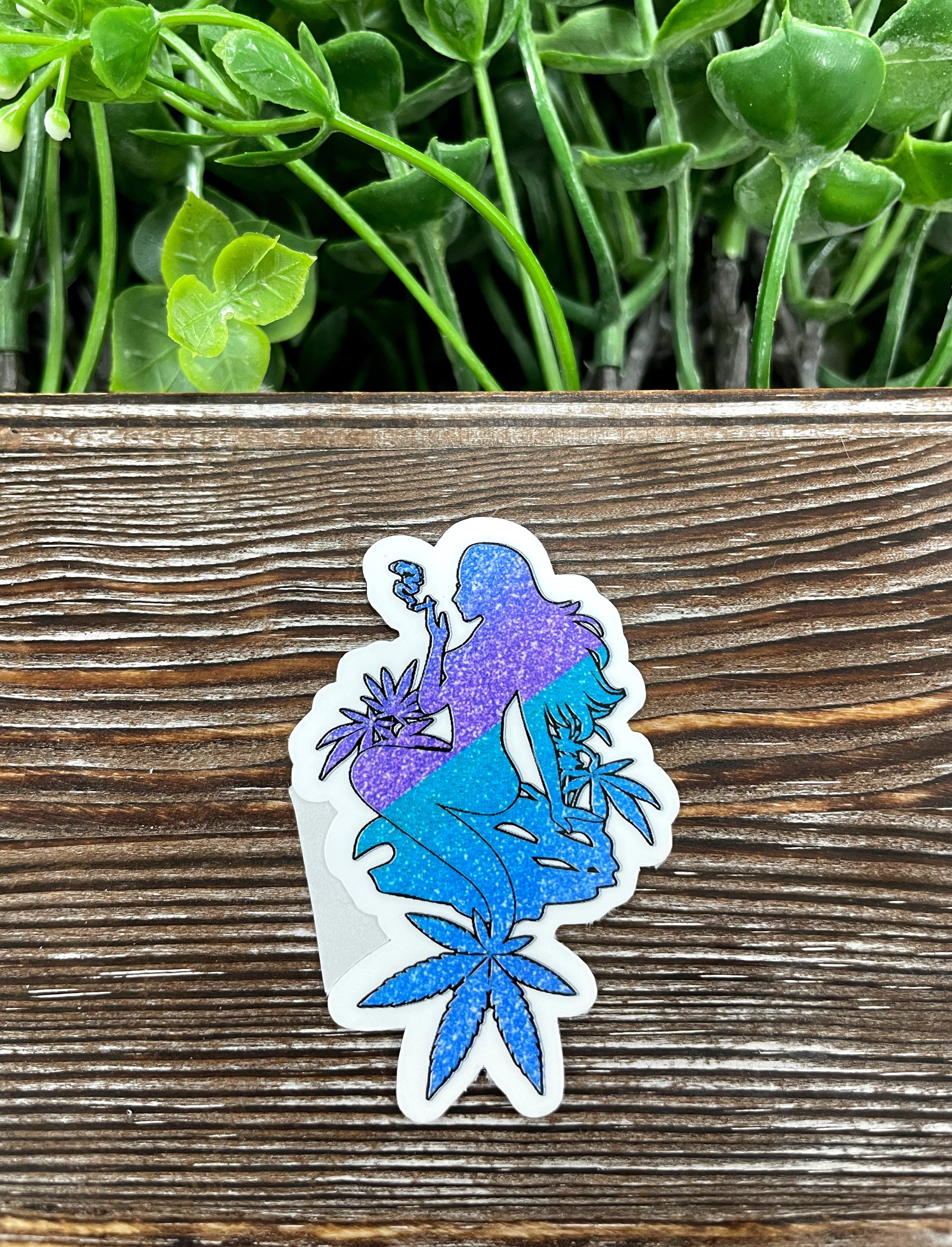 Blue and purple glitter mermaid die cut sticker on a smooth surface, showcasing vibrant colors and intricate design.