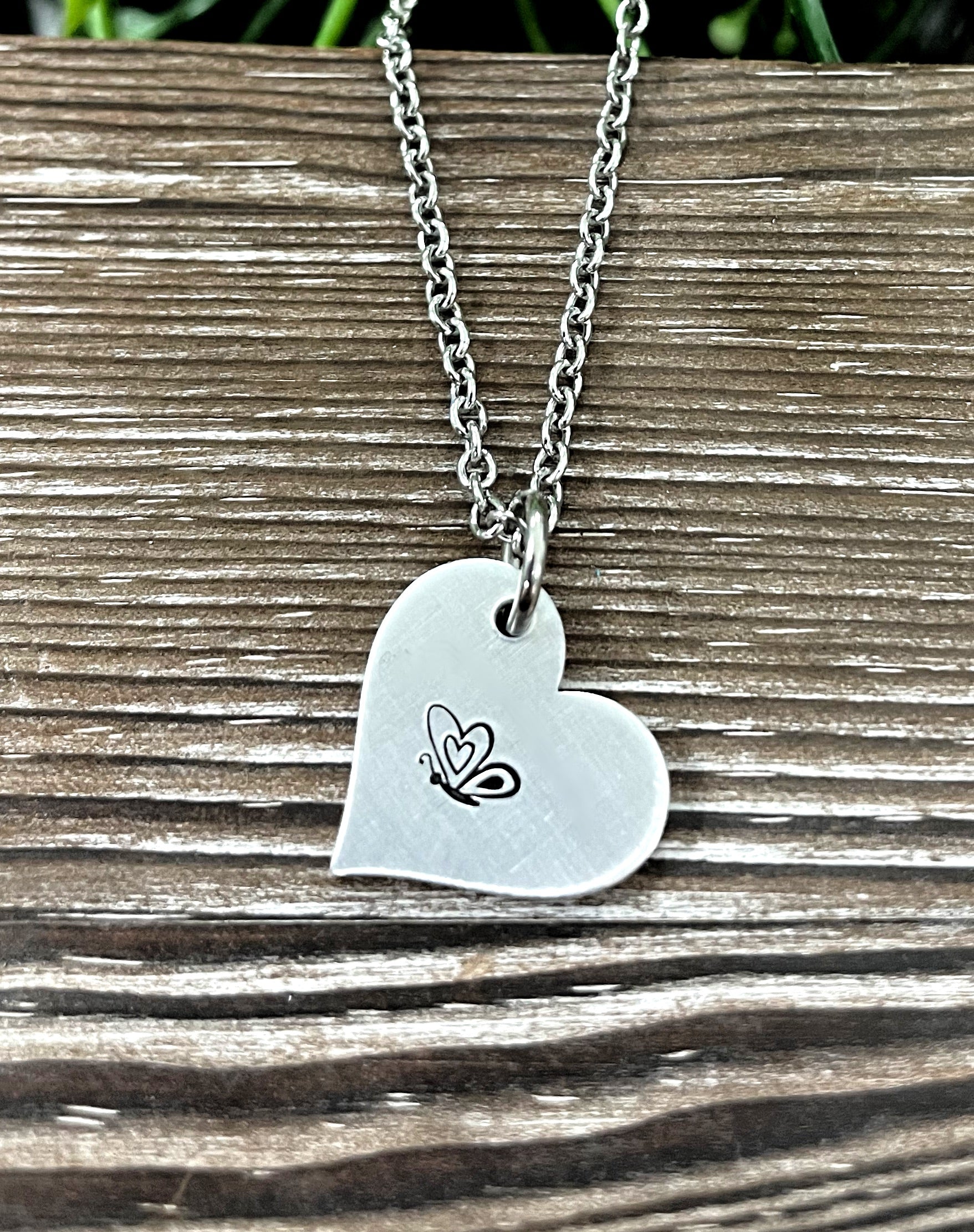 A beautifully crafted Butterfly Heart Hand Stamped Necklace featuring a unique design, showcasing the handmade quality and charm.