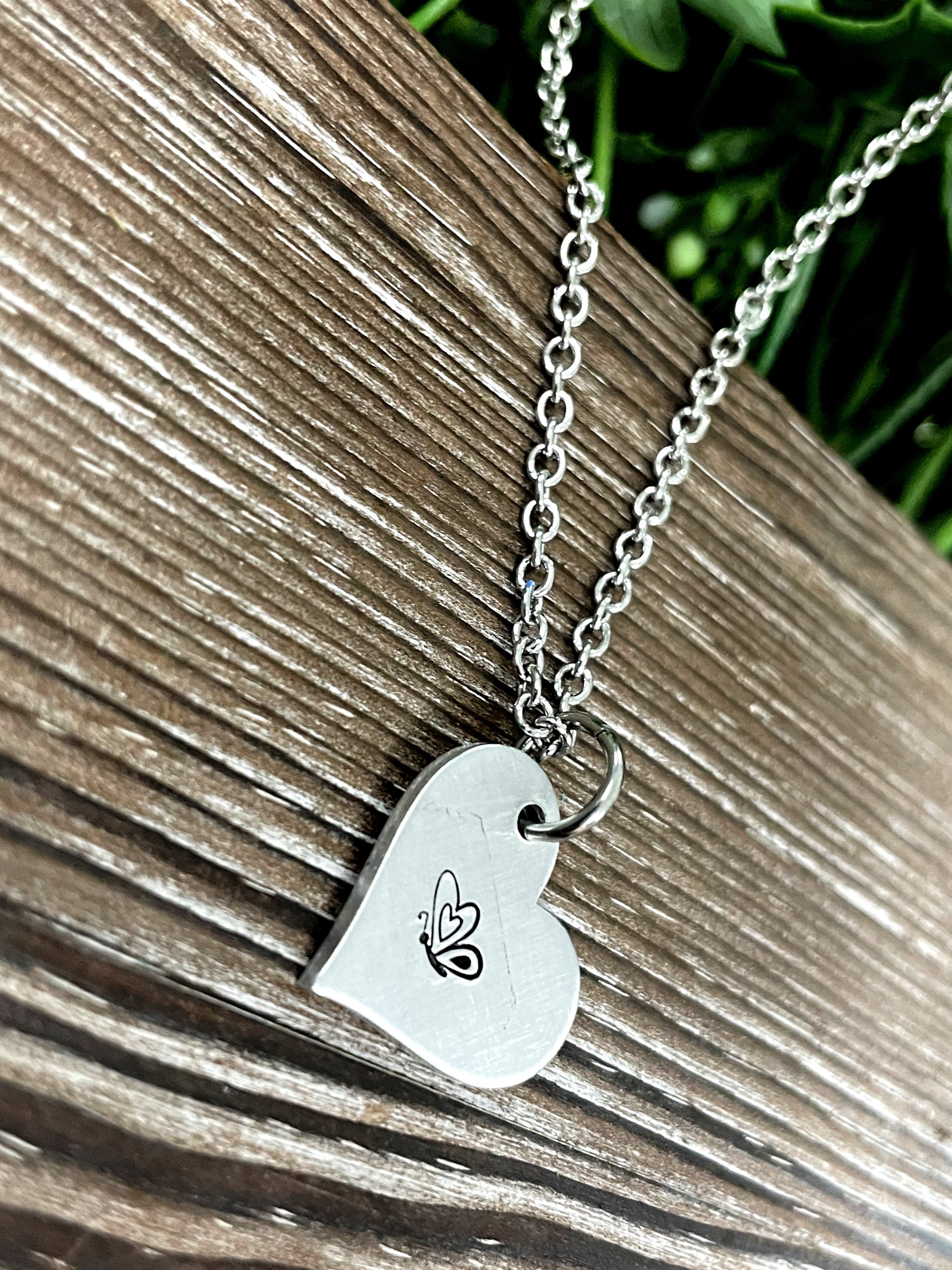 A beautifully crafted Butterfly Heart Hand Stamped Necklace featuring a unique design, showcasing the handmade quality and charm.