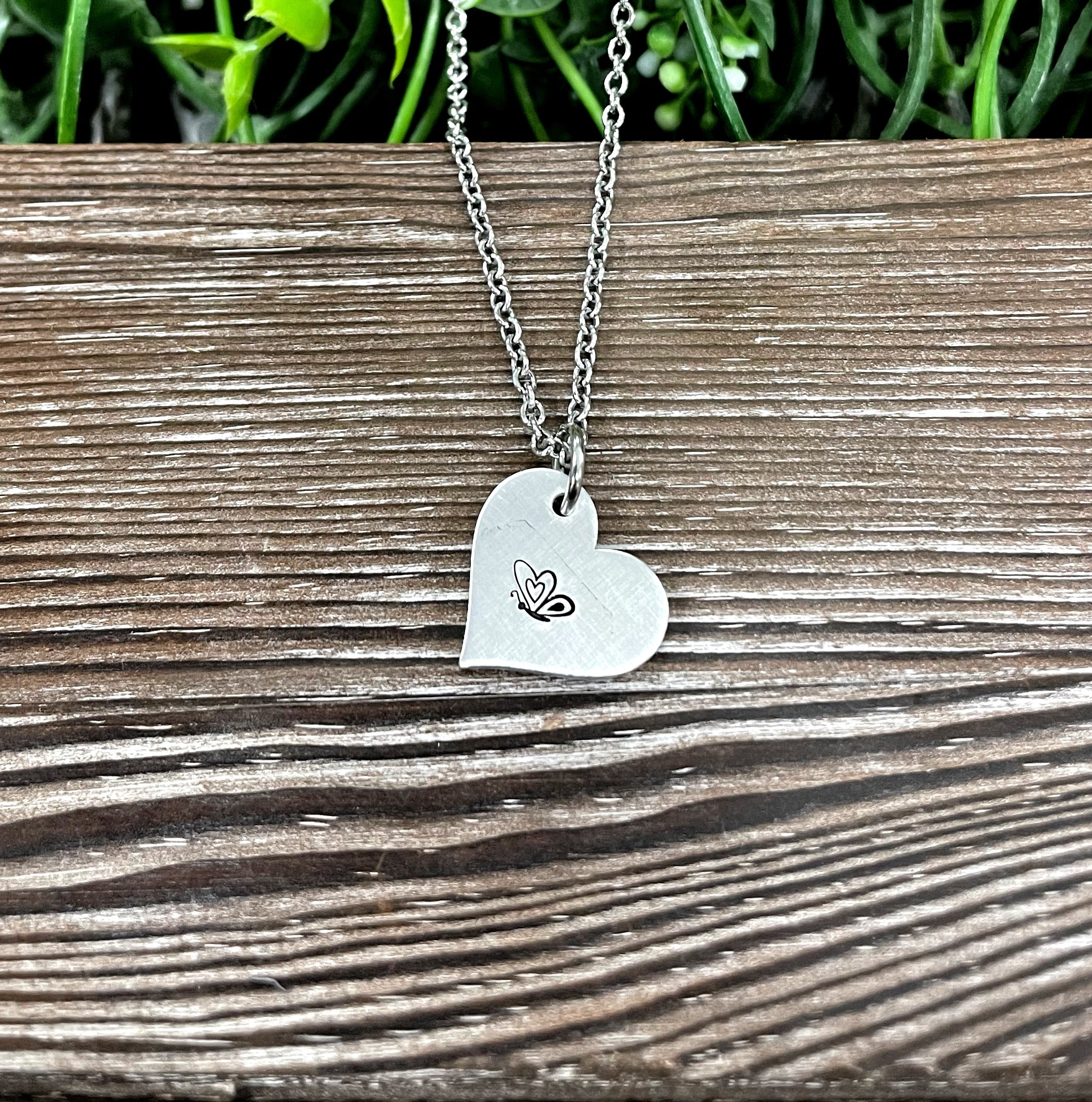 A beautifully crafted Butterfly Heart Hand Stamped Necklace featuring a unique design, showcasing the handmade quality and charm.