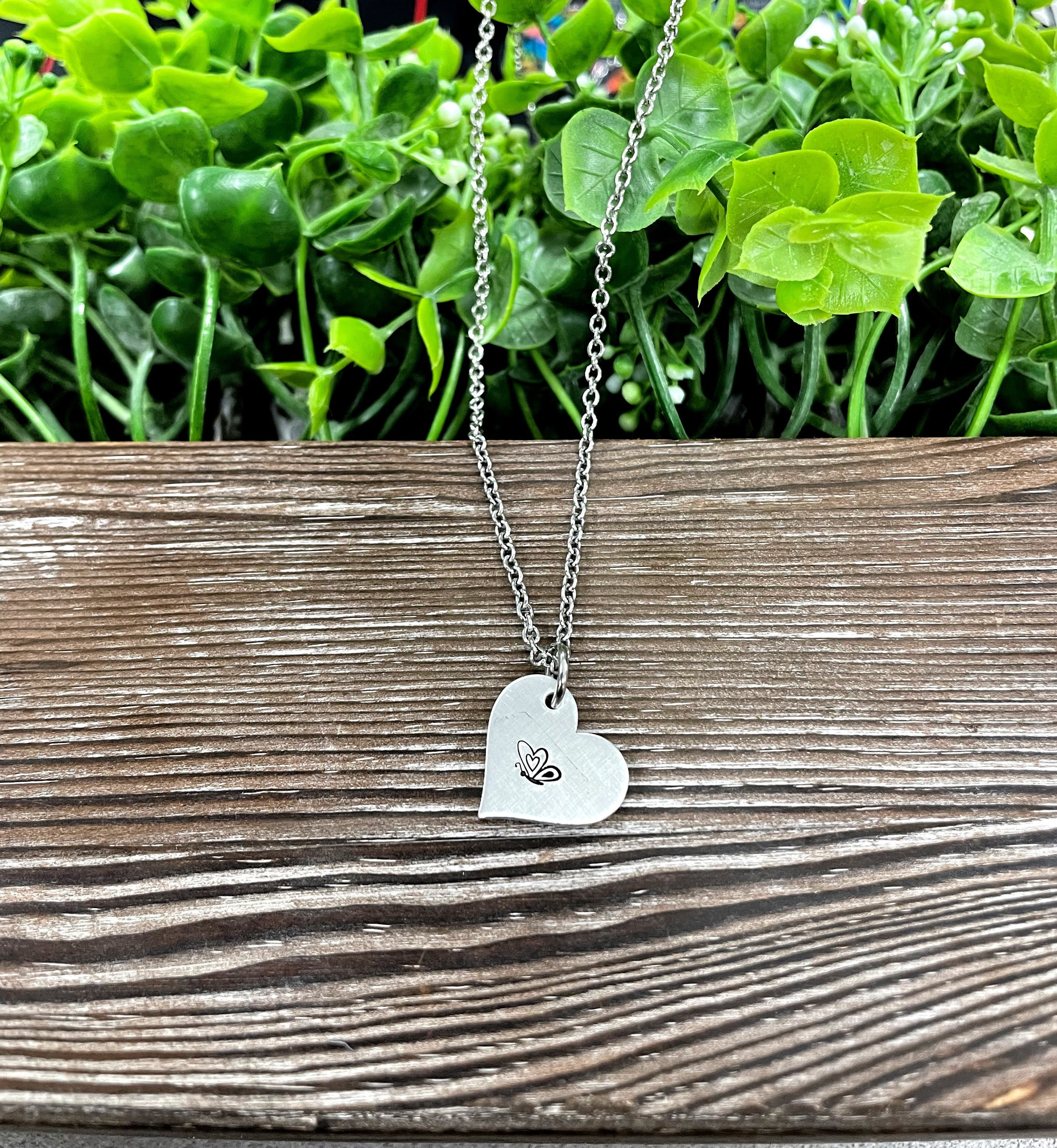 A beautifully crafted Butterfly Heart Hand Stamped Necklace featuring a unique design, showcasing the handmade quality and charm.