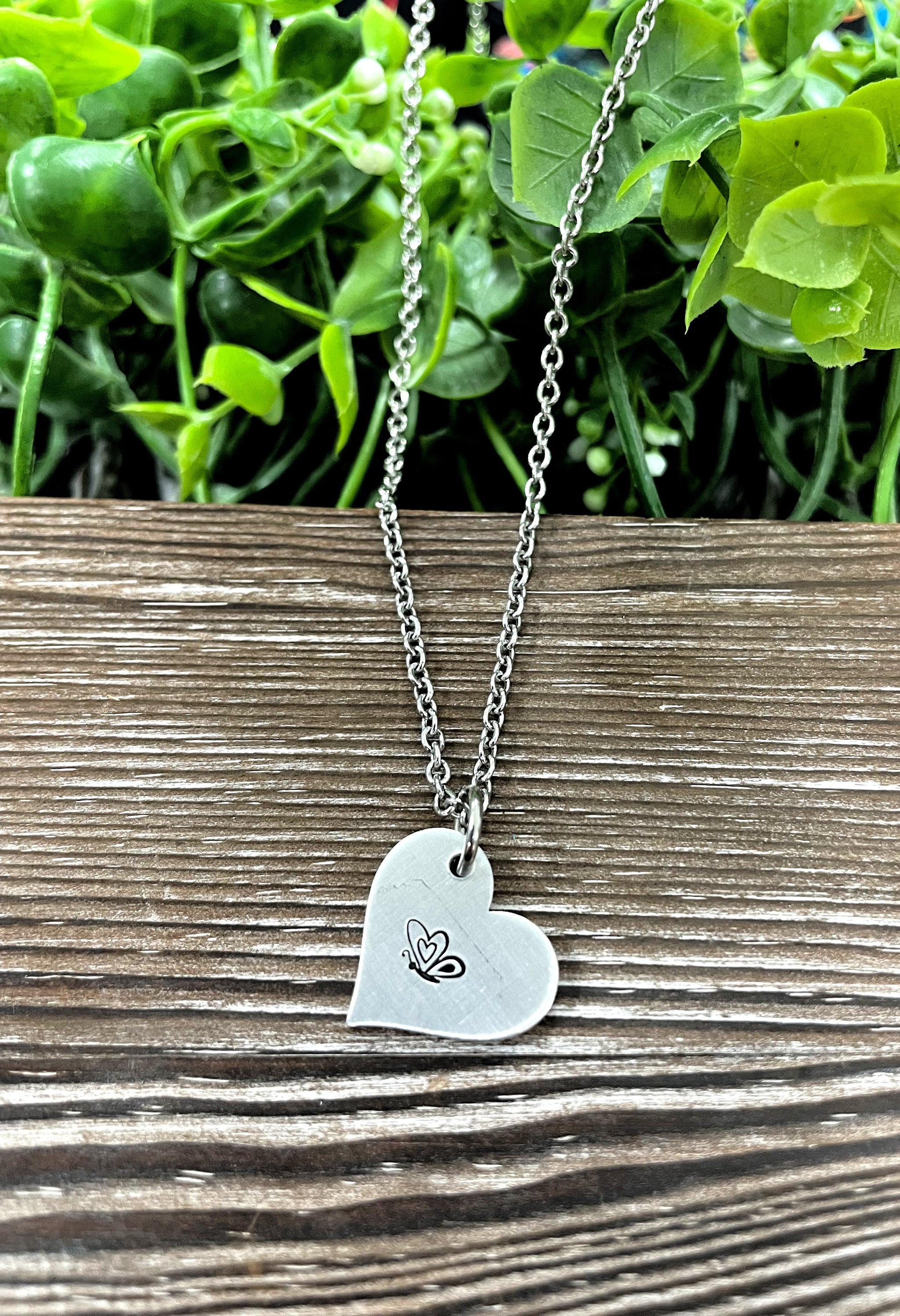 A beautifully crafted Butterfly Heart Hand Stamped Necklace featuring a unique design, showcasing the handmade quality and charm.